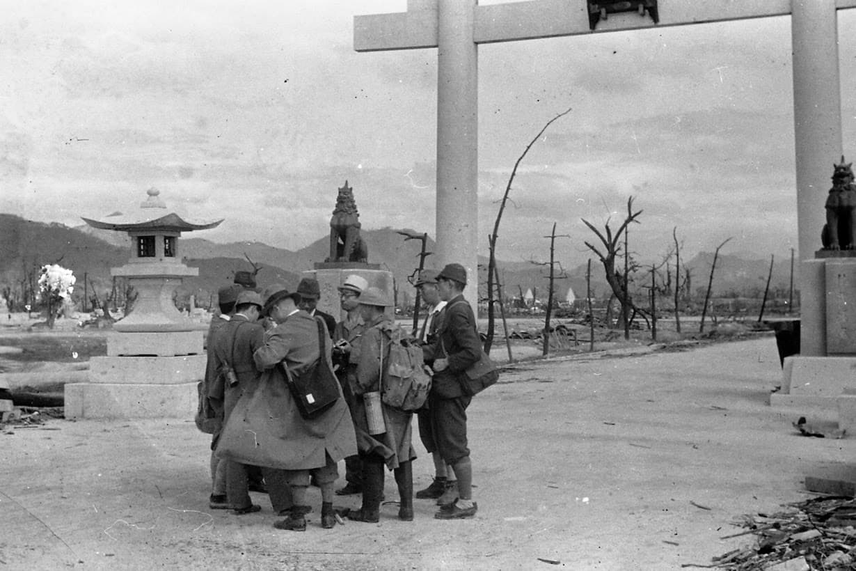 Survey team members confer in front of the large torii gate on the approach to Hiroshima Gokoku Shrine after the atomic bombing of Hiroshima, in Moto-machi district.