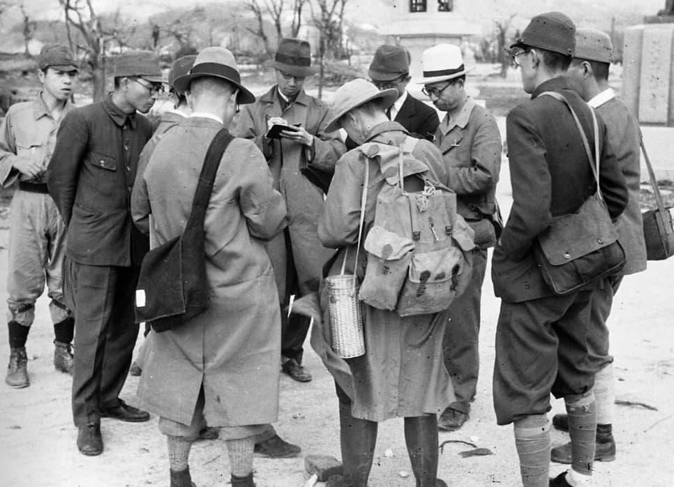 Survey team members confer in front of the large torii gate on the approach to Hiroshima Gokoku Shrine after the atomic bombing of Hiroshima, in Moto-machi district.