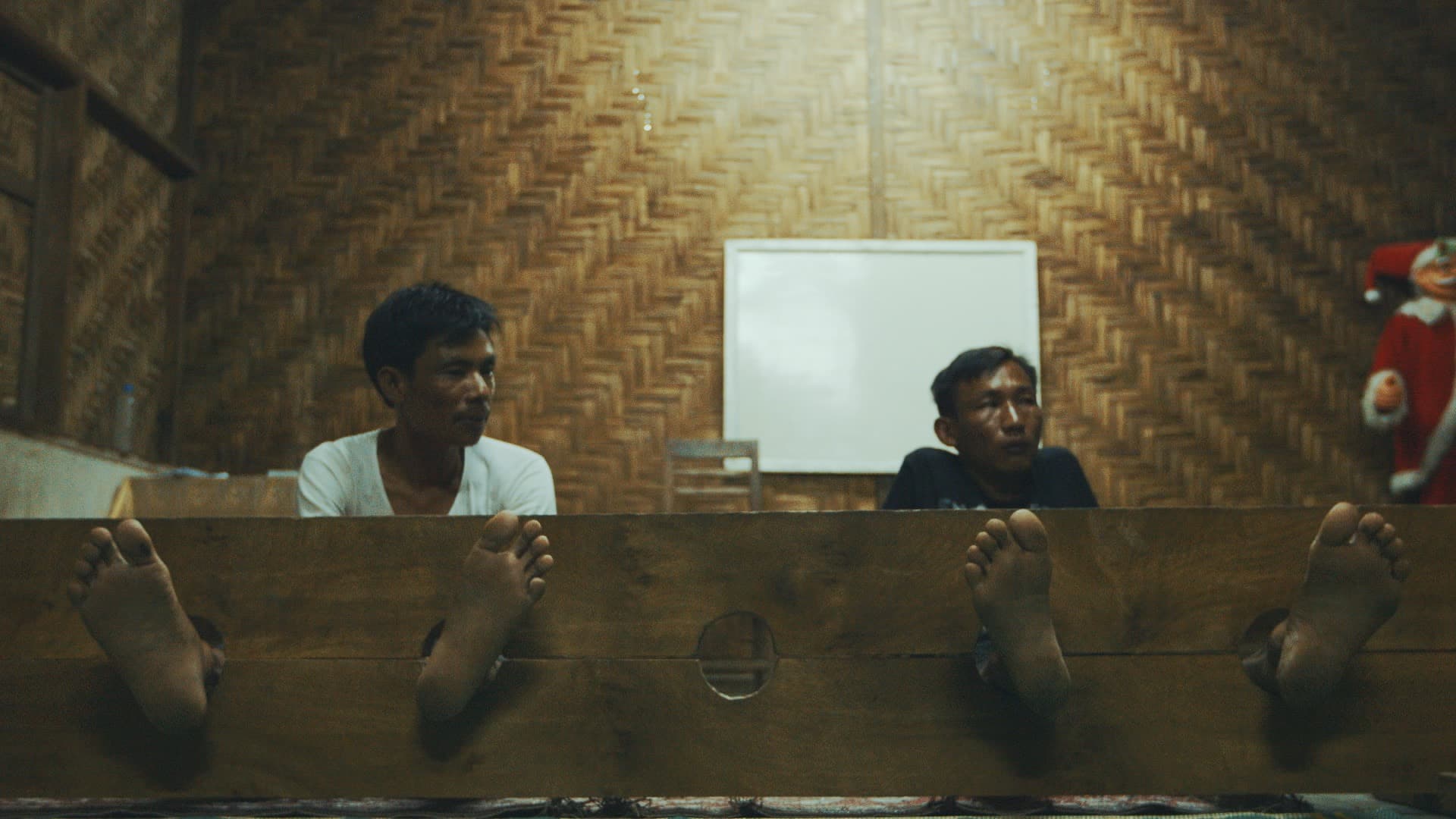 La Seng, right, stuck in stocks with another accused drug user.