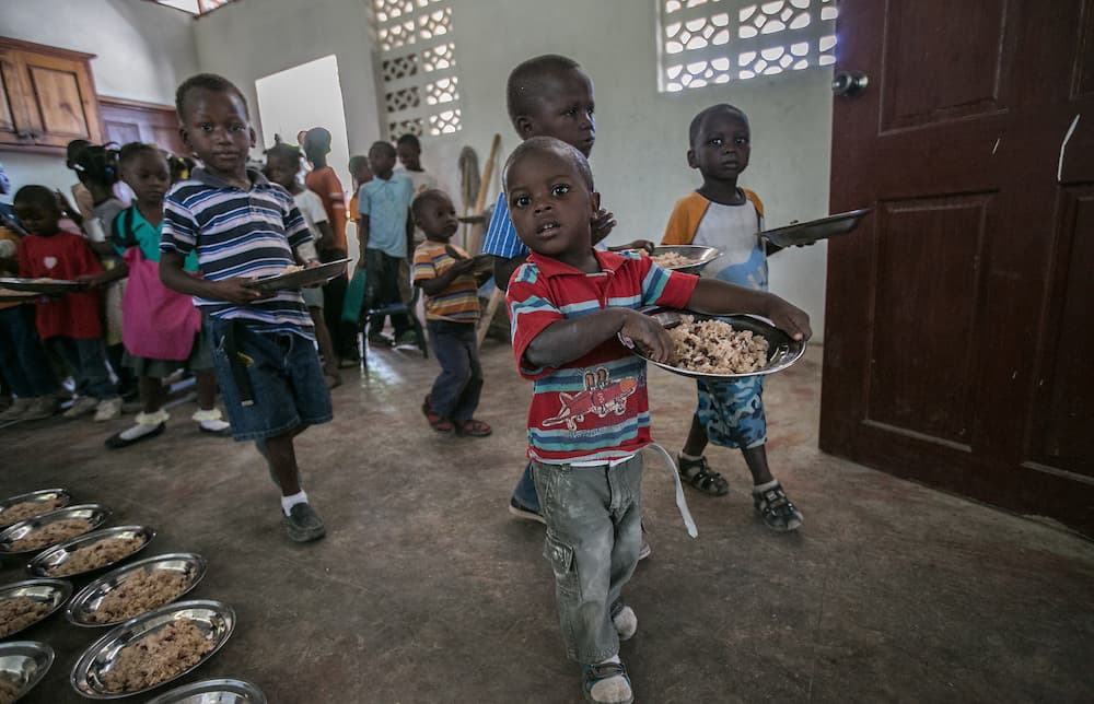 Migrant children at the Notre Dame de Lourdes School in Anse-a-Pitres, Haiti, pick up lunch after class.