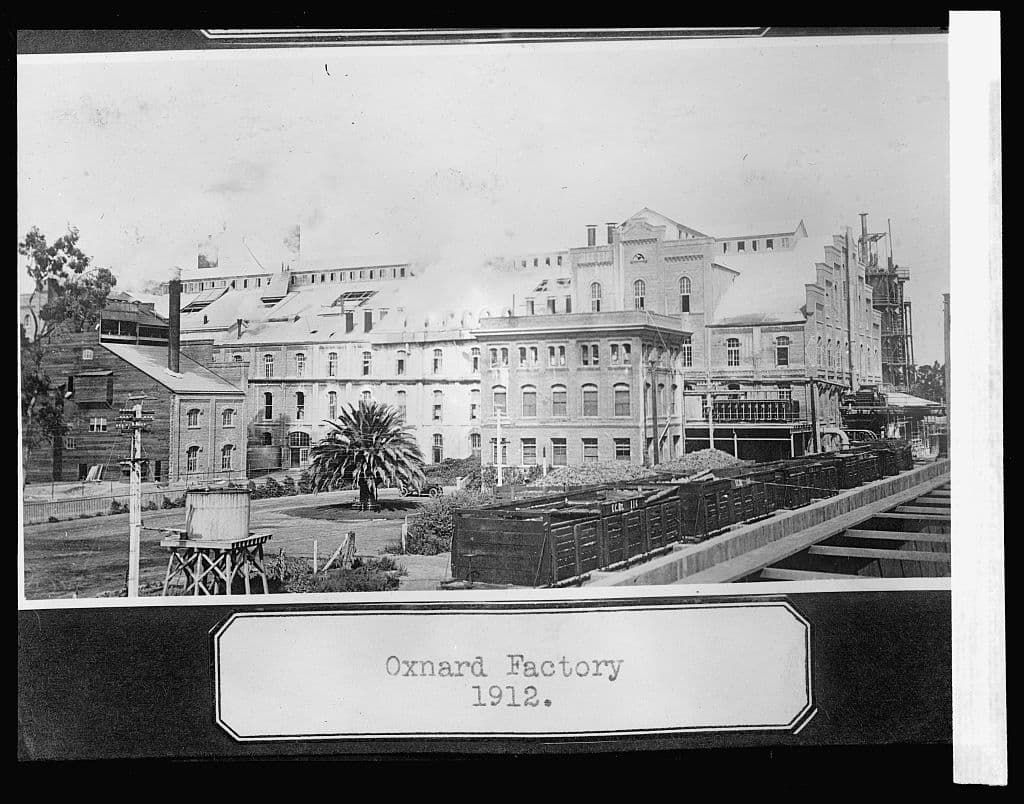 A black and white photo of a factory, with the label 