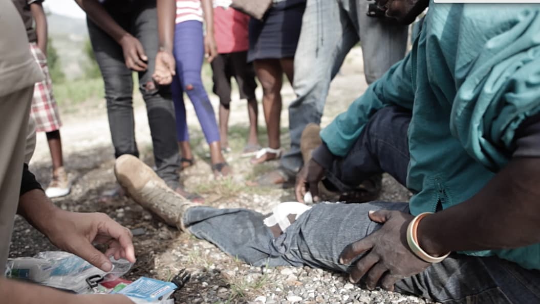 Onlookers attend to a man who crashed his motorcycle far from any hospital. Road accidents are common in Haiti, and frequently deadly as people don’t wear helmets.