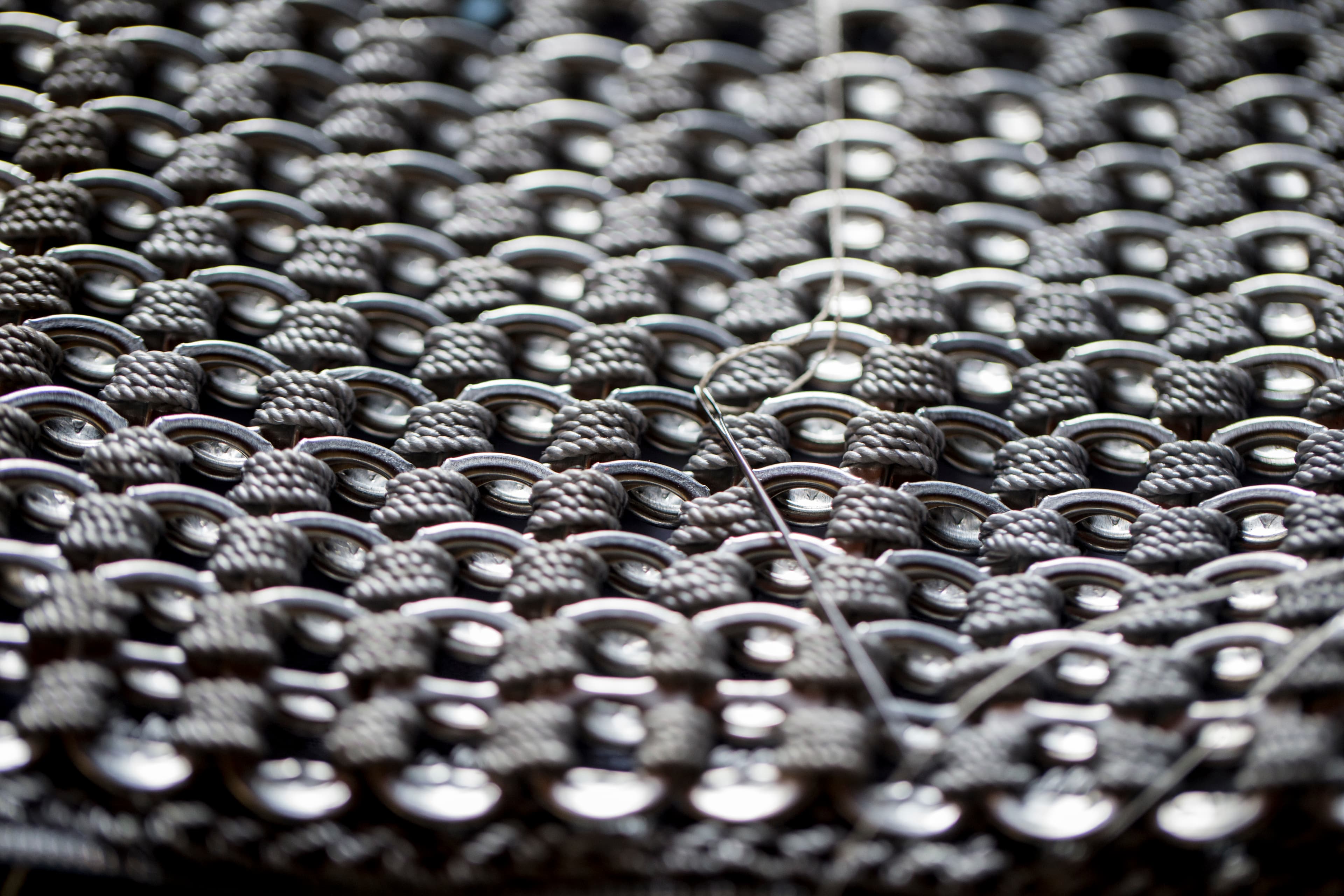 A women's purse made of soda can openers sewn together.