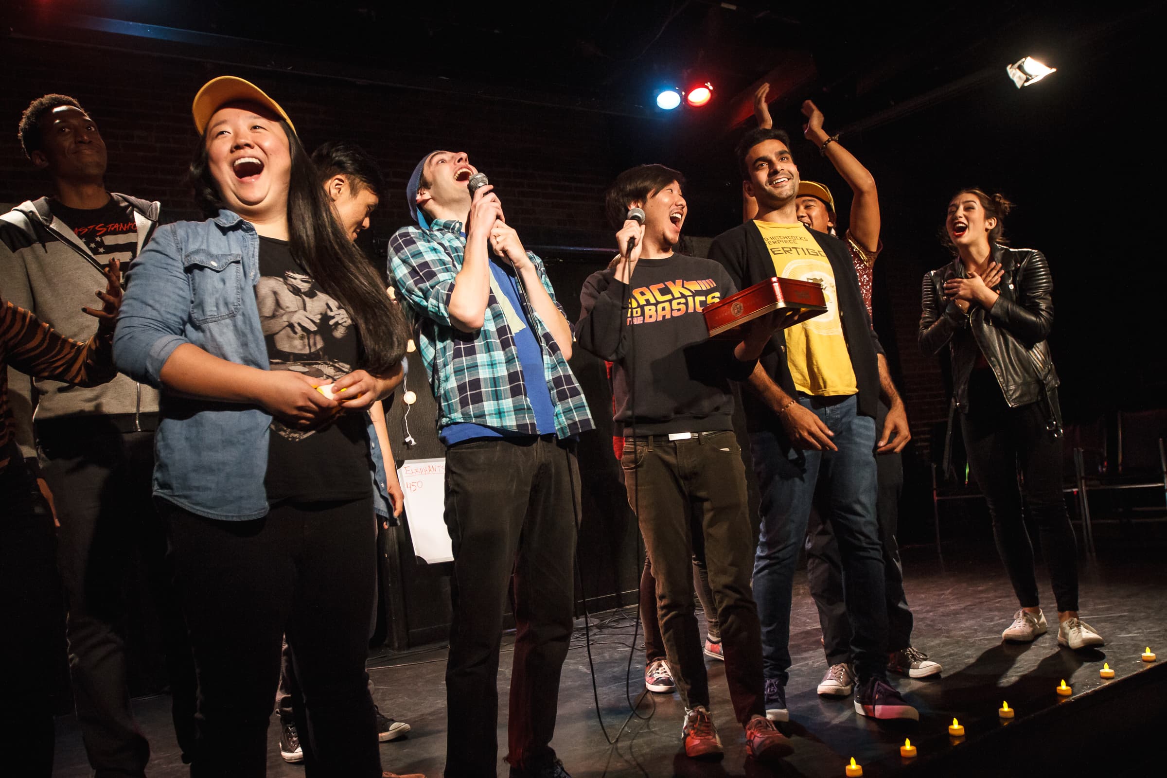 At least eight performers are onstage as the winners are announced in the rap battle. They are laughing and clapping.