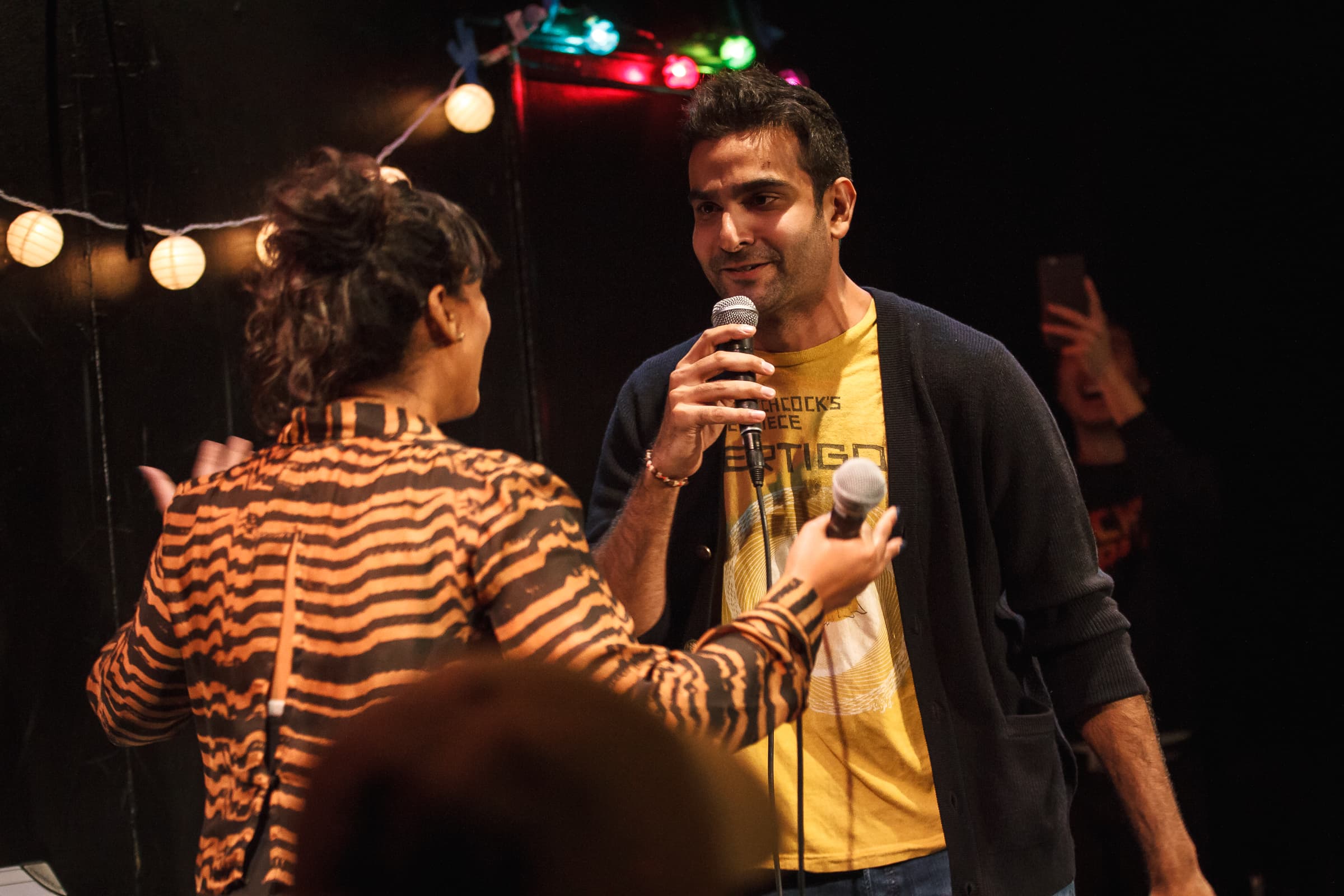A man smiles while listening to his opponent in a rap battle.