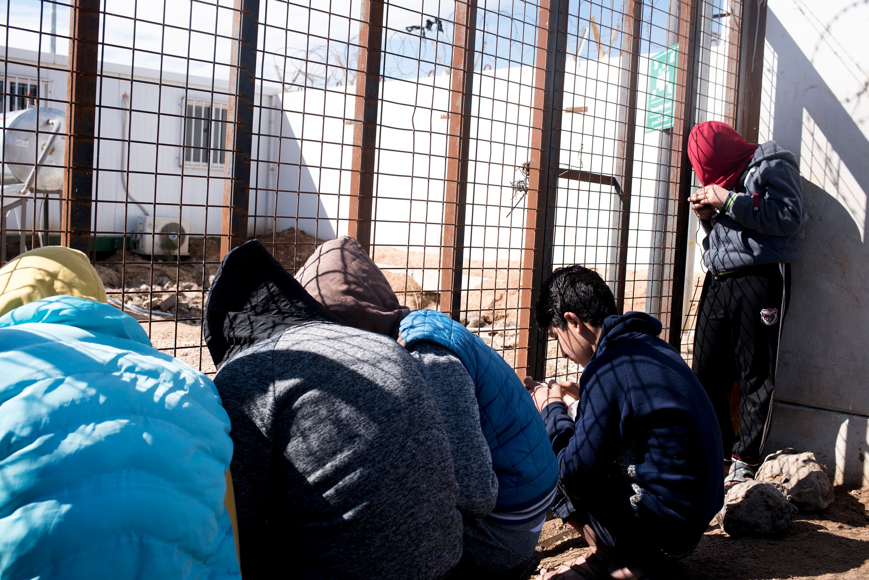 Zaatari residents try to access the internet at the gated entrance of the camp's humanitarian aid compound. Though organizations have discussed implementing camp-wide wifi, the humanitarian hub remains the only place with reliable service in the sprawling