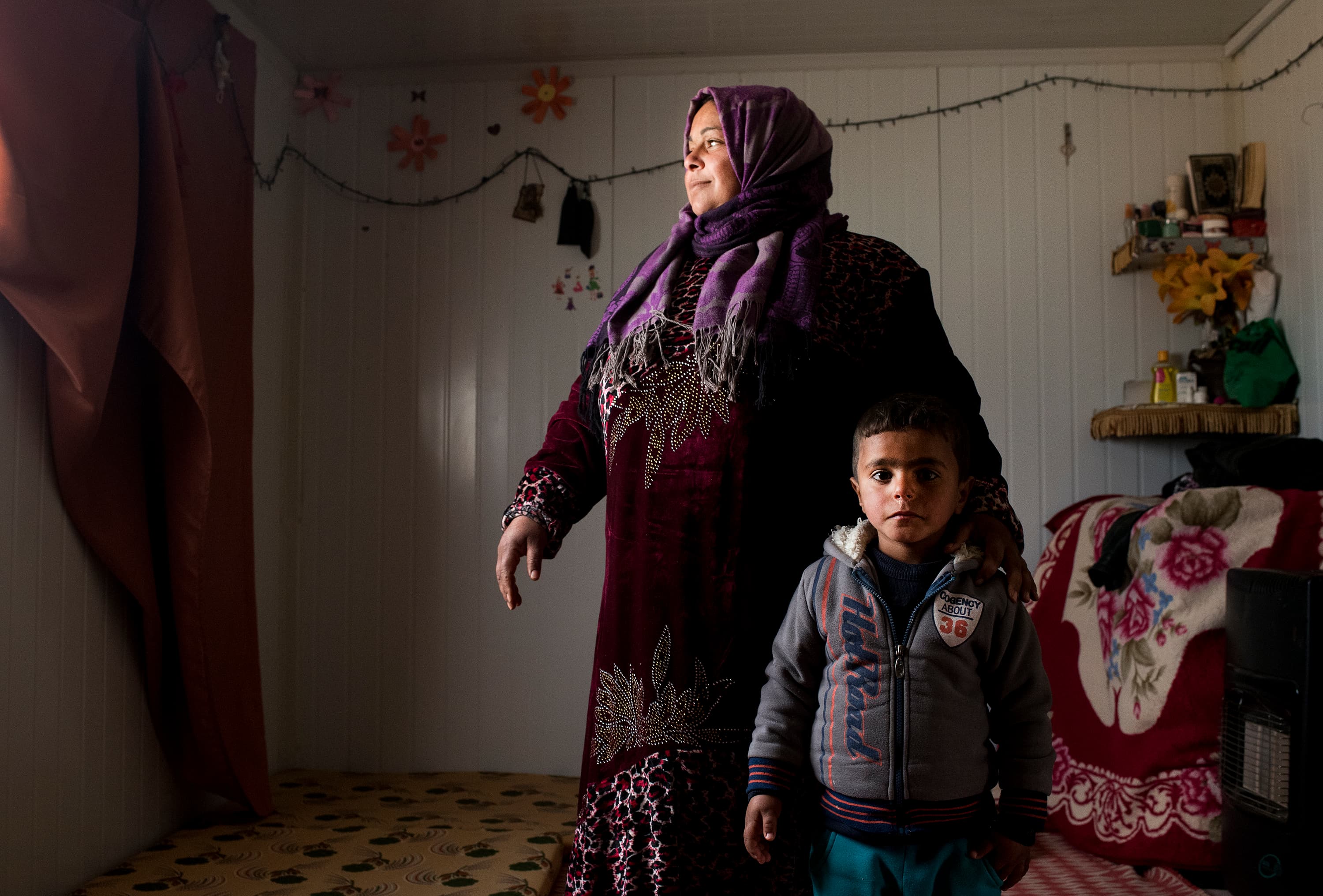 Um Ala and one of her children, Zakaria, 3, pause inside the family's metal shelter in Jordan's Zaatari refugee camp. Her two youngest children have never seen Syria.