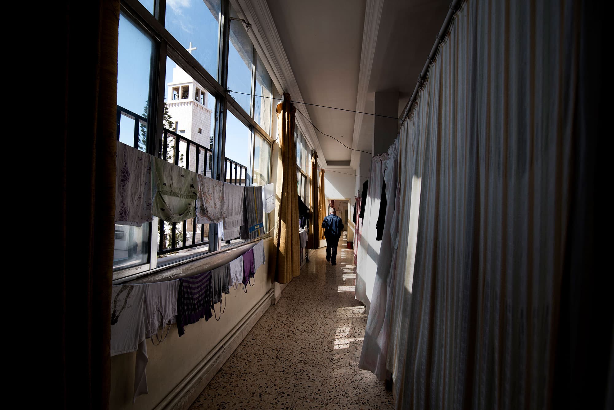 Numair Faisal Elyas makes his way down a corridor of the St. Mary's Church in Marka. The father of three has lived in the church hall with his family since August 2014.