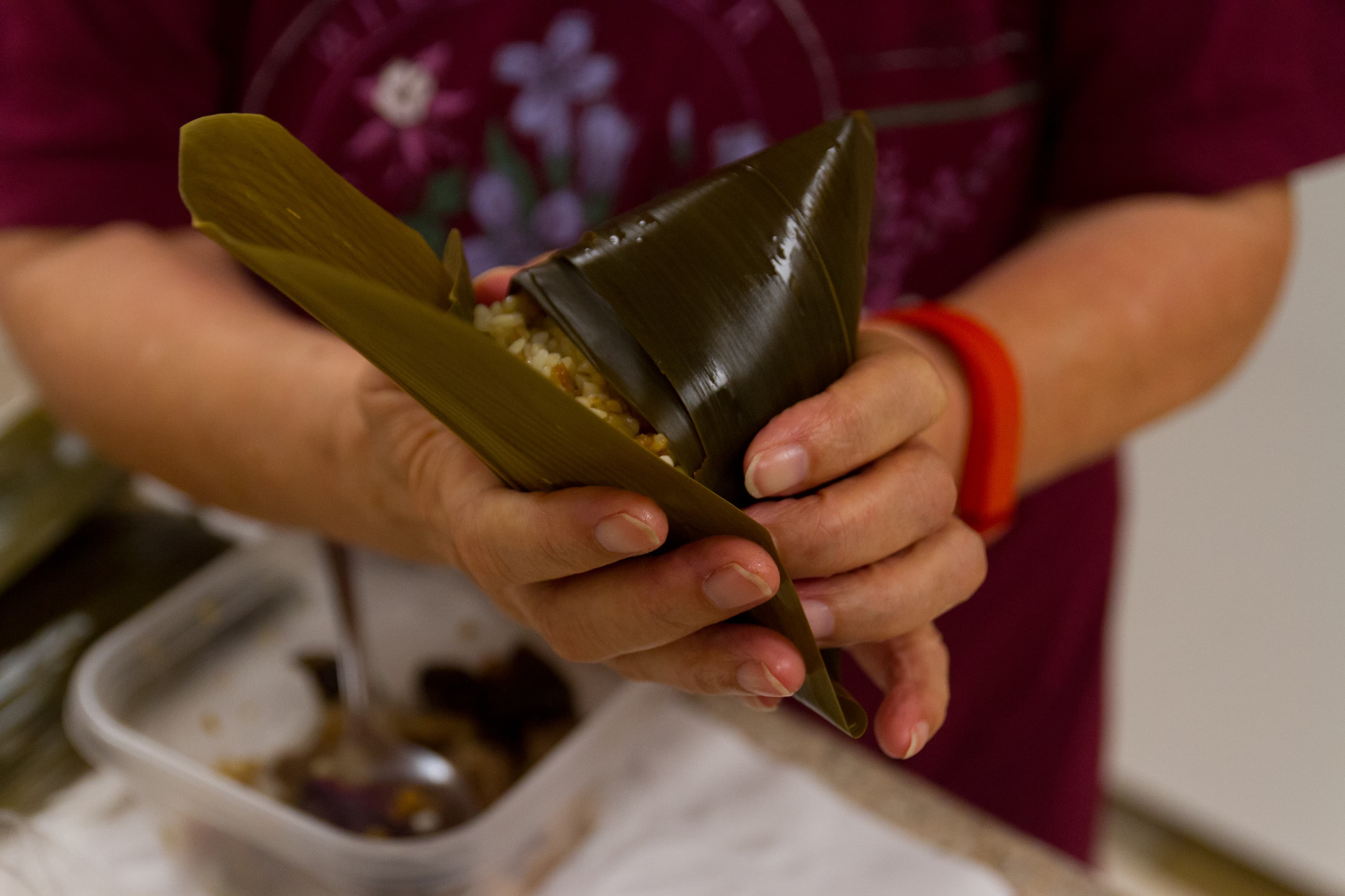 Woman's hands gently closes bamboo leaf into a dumpling