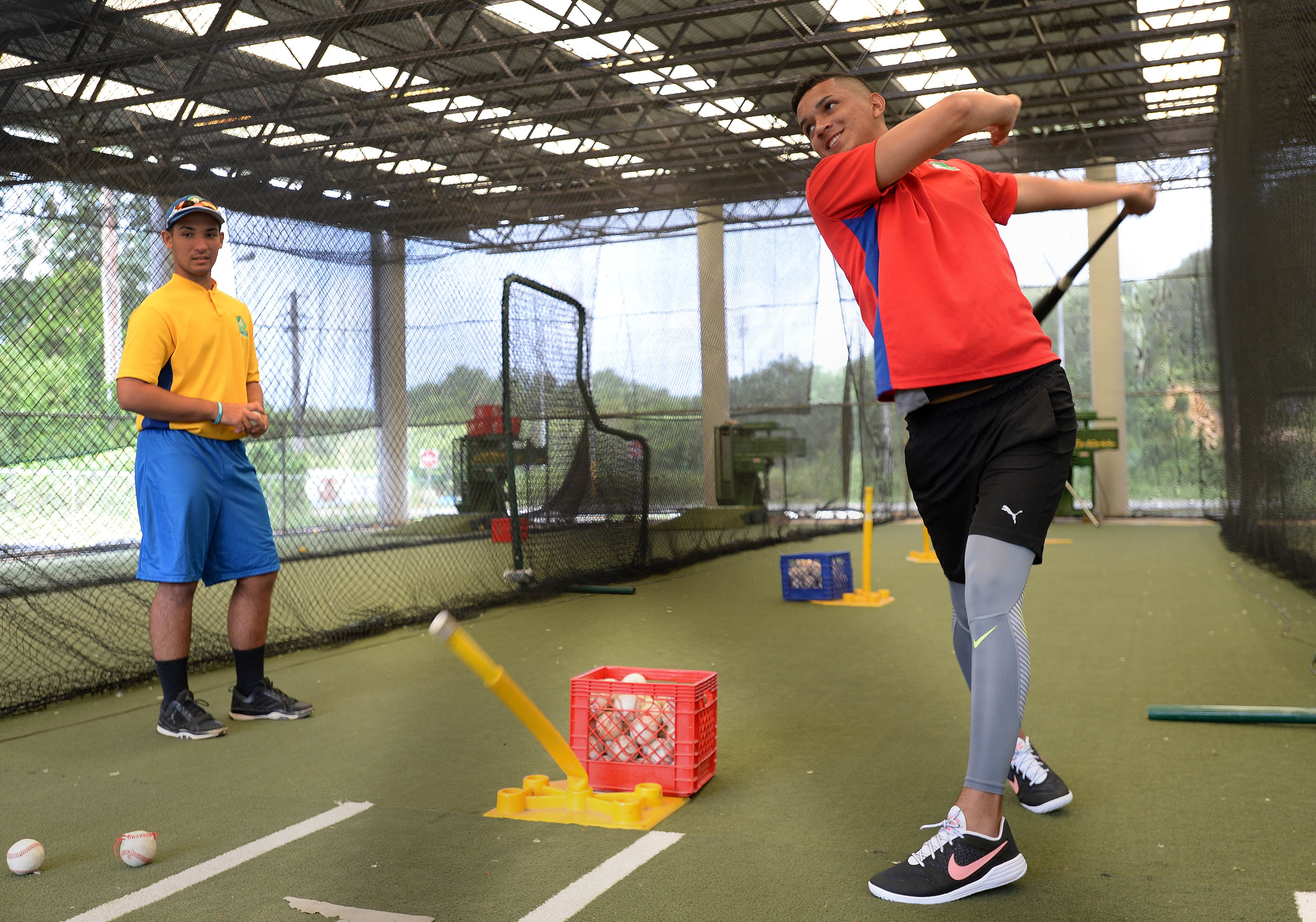 Luis Virella takes a swing in the batting cage as Manuel Castillo waits his turn.