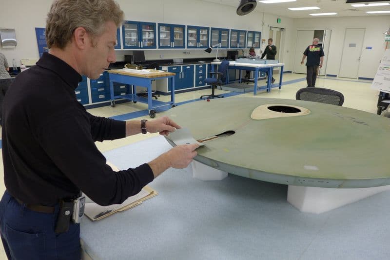 Museum Specialist David Wilson finds the exact color match to the grey paint inside the saucer.