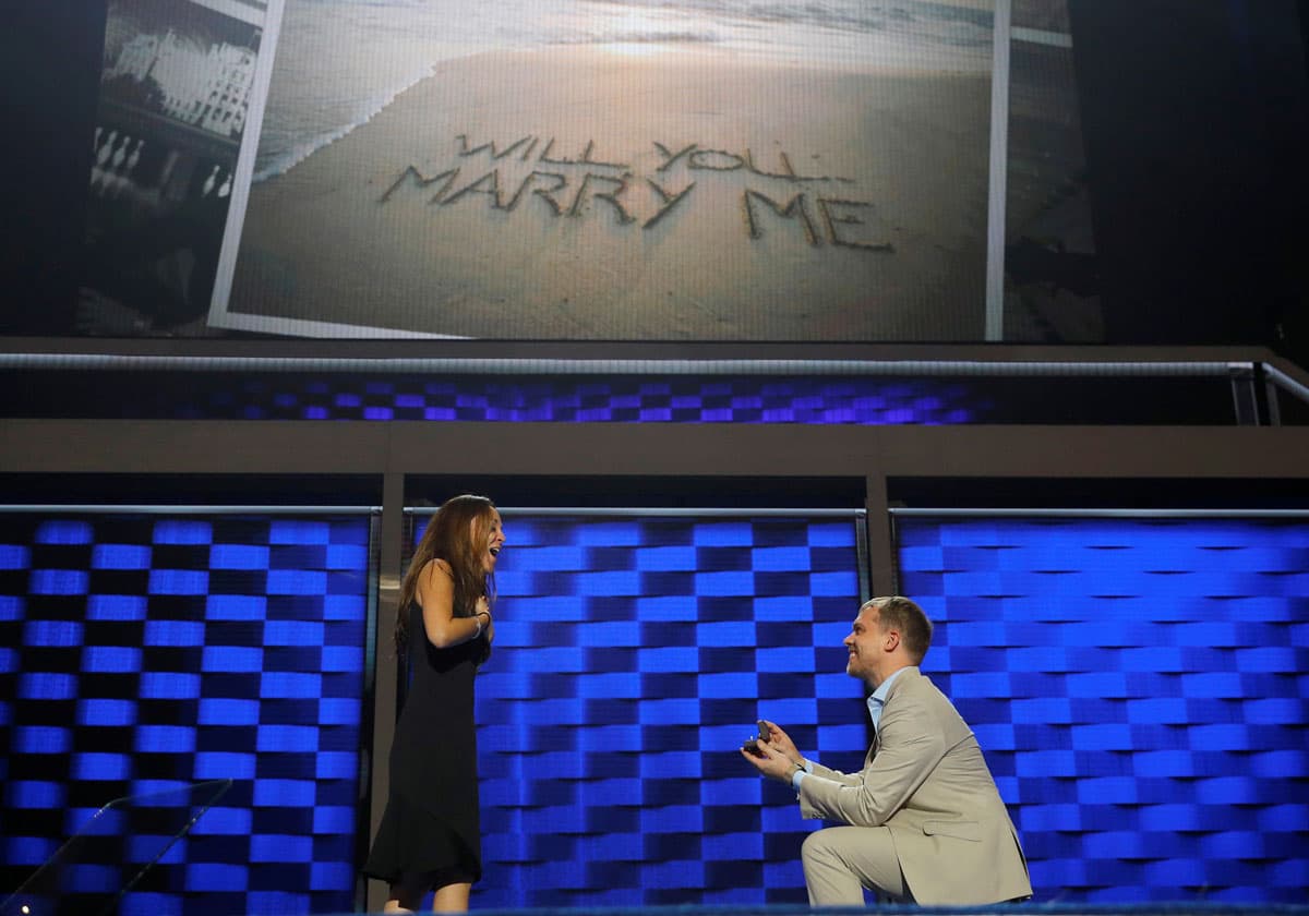 Hillary Clinton campaign staffer Liz Hart (L) reacts as fellow campaign staffer Andrew Binns proposes on stage at the Wells Fargo Center the day before the DNC.