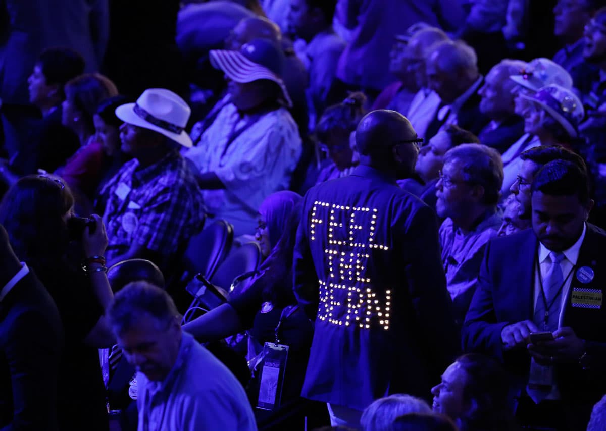 A supporter of former Bernie Sanders makes his way past delegates at the DNC.
