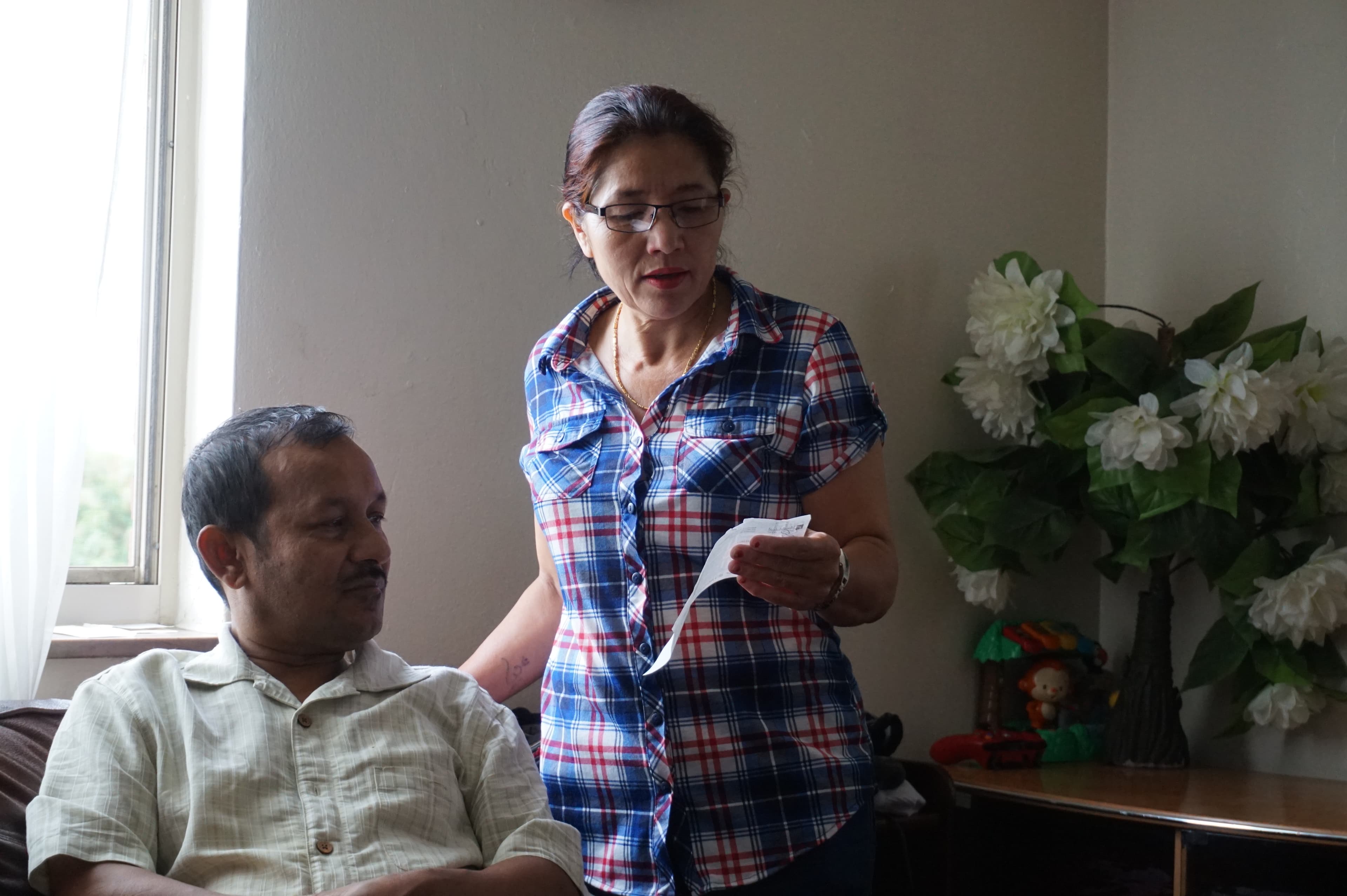 Man sitting, with woman standing beside holding paper in front of them