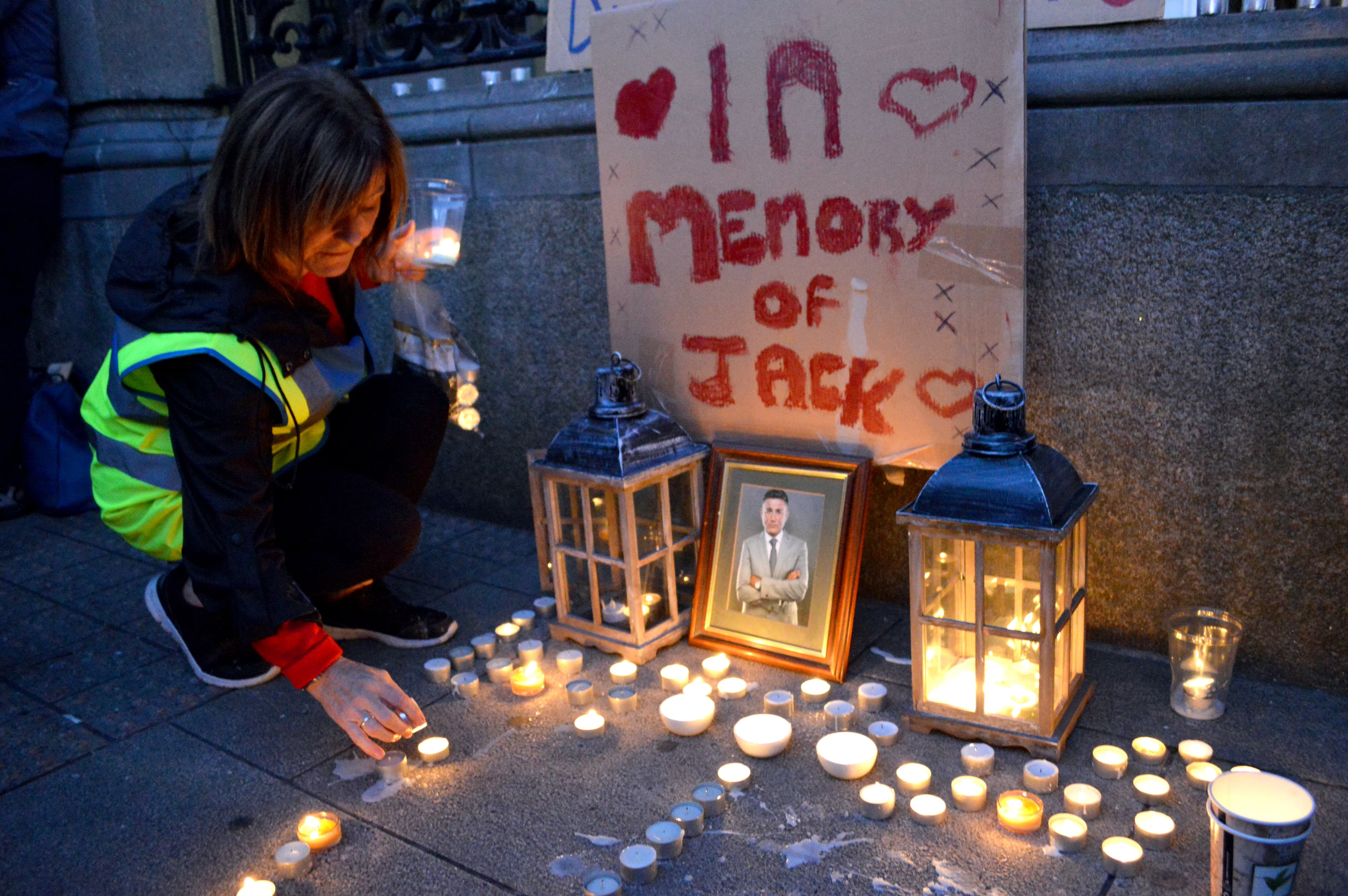 woman lighting candles at a vigil of a homeless man