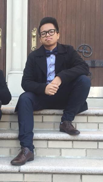 Young man sits on steps of a building