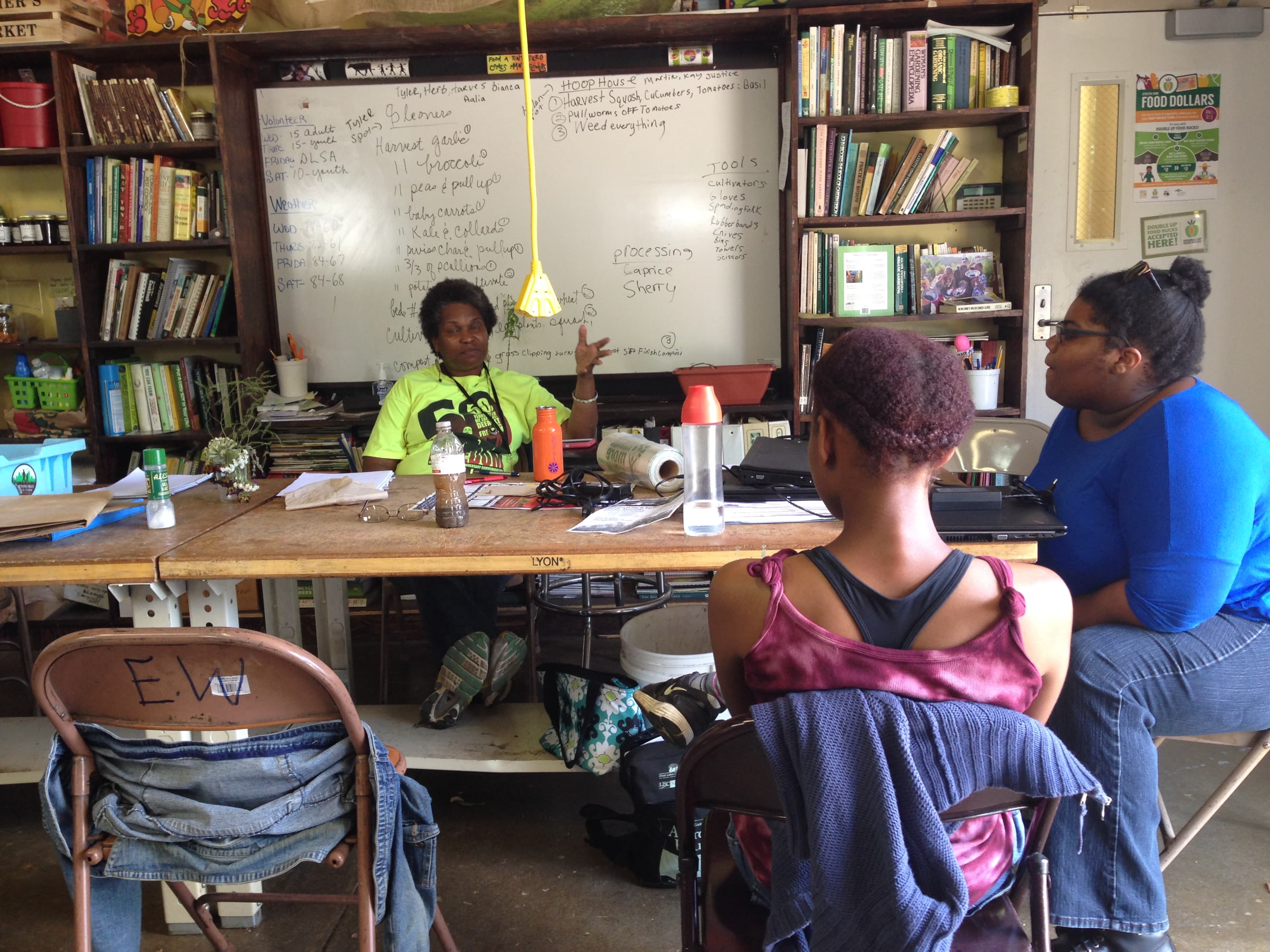 Ra Barber sits behind a desk talking to two students in front