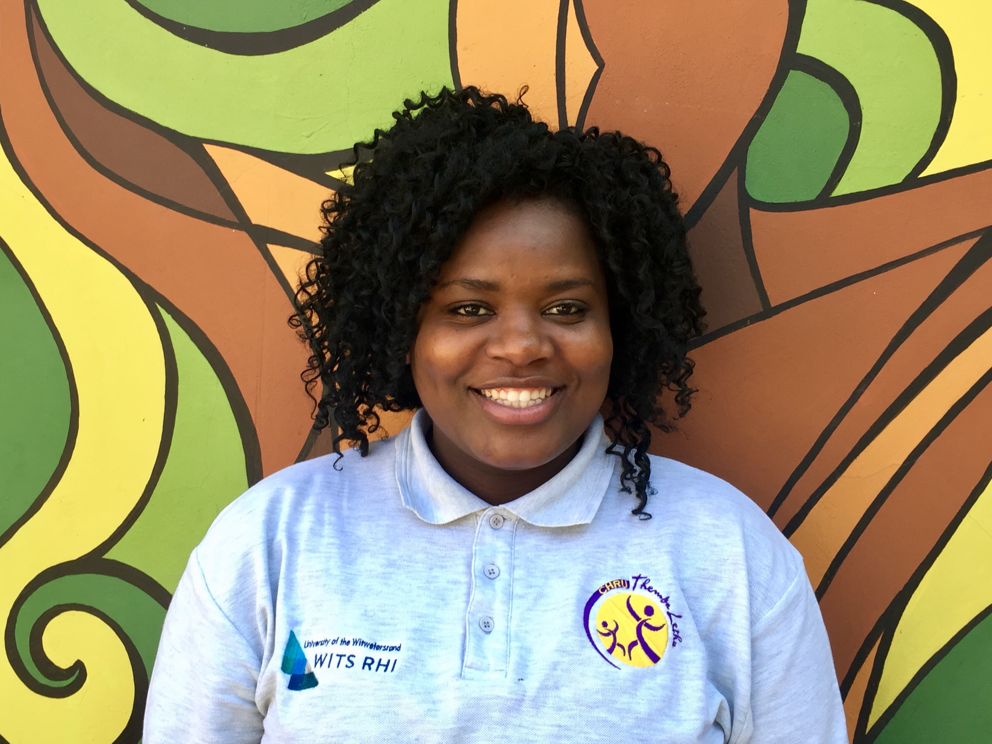 Awelani Neluonde stands in front of a mural outside of hospital in Johannesburg.
