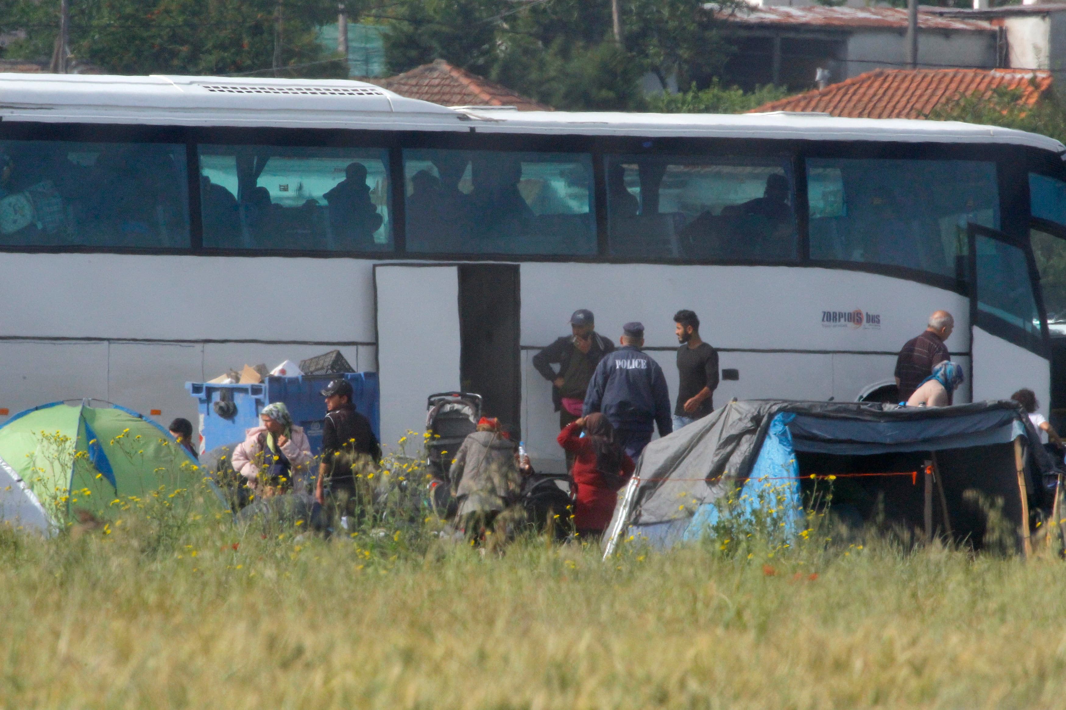 Police watch as refugees and migrants board buses to be tranferred to government camps, during an operation to evacuate a makeshift camp at the Greek-Macedonian border near the village of Idomeni, Greece, May 24, 2016.