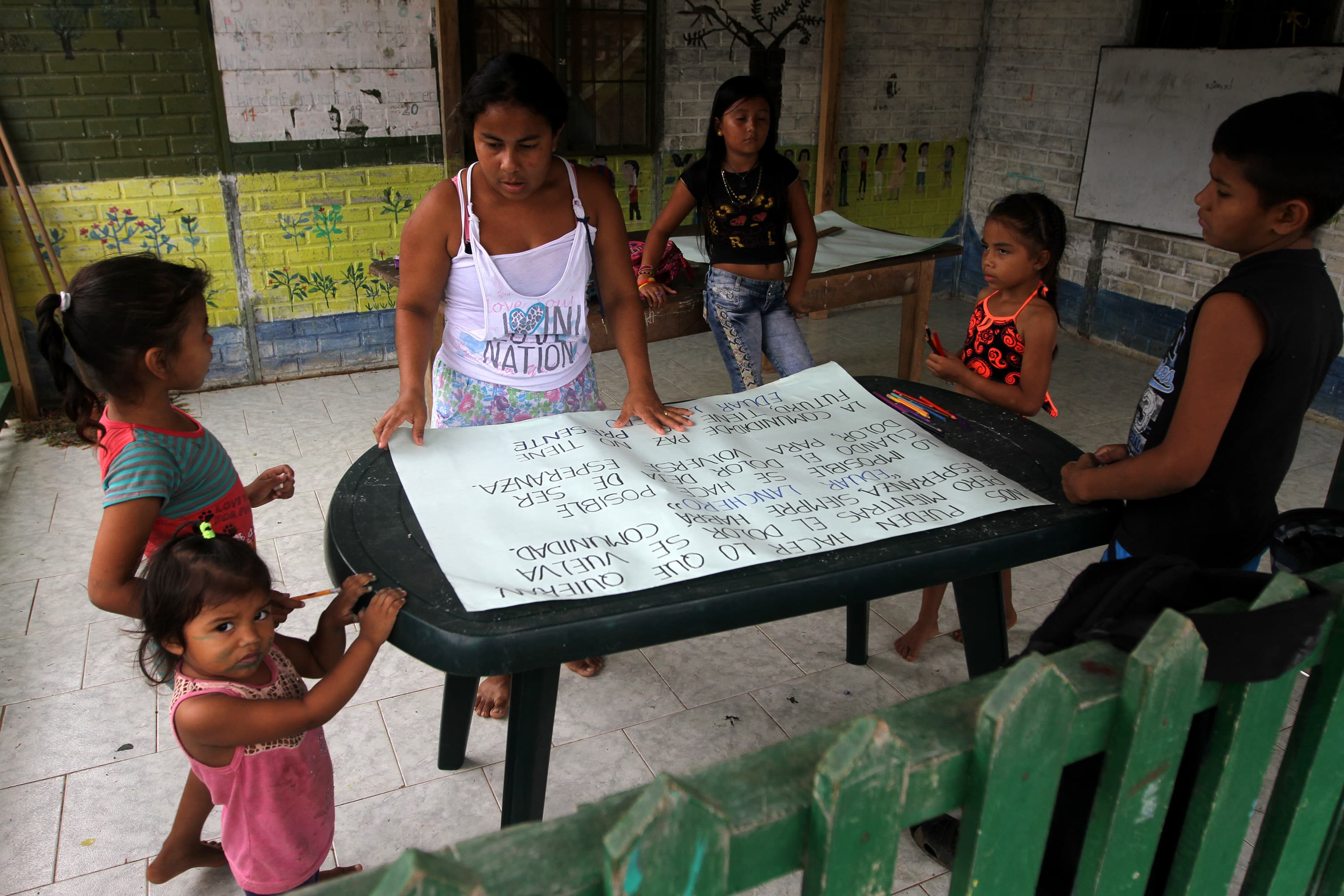 Kids making signs with quotes from community leader Eduar Lanchero about hope, forgiveness, for 19th anniversary