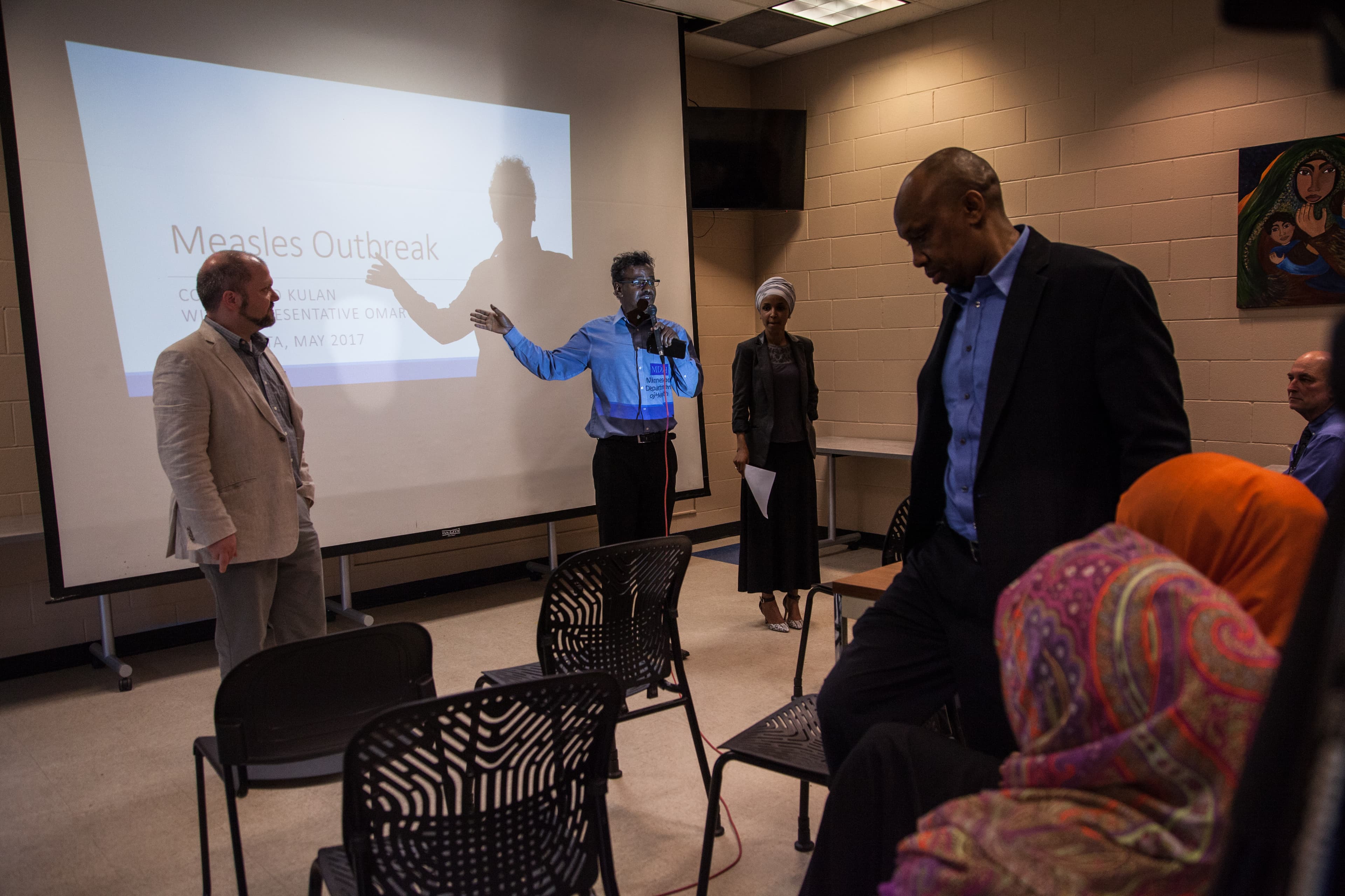 Man at center with microphone in front of screen
