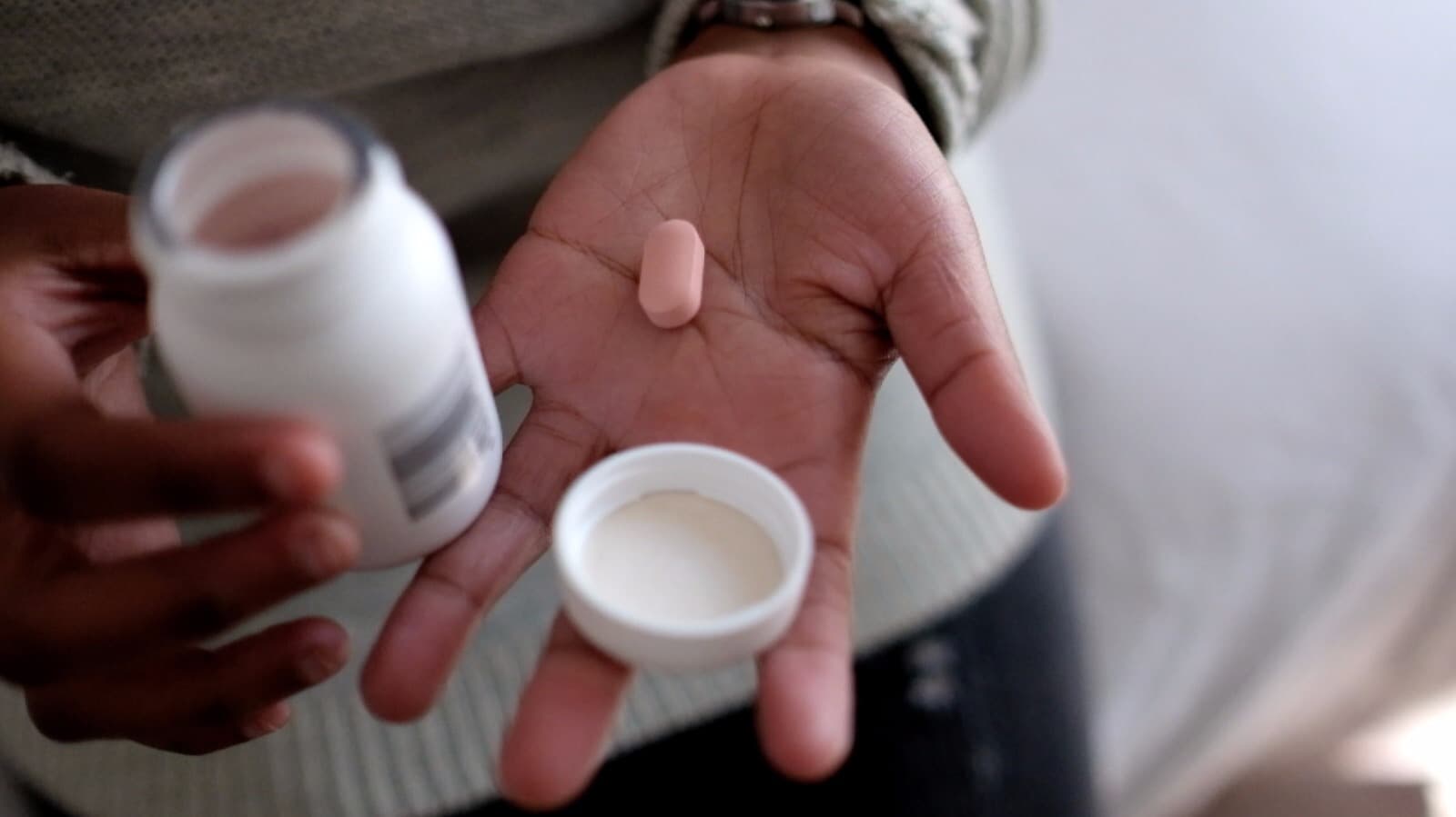Close-up of a hand holding antiretroviral tablets