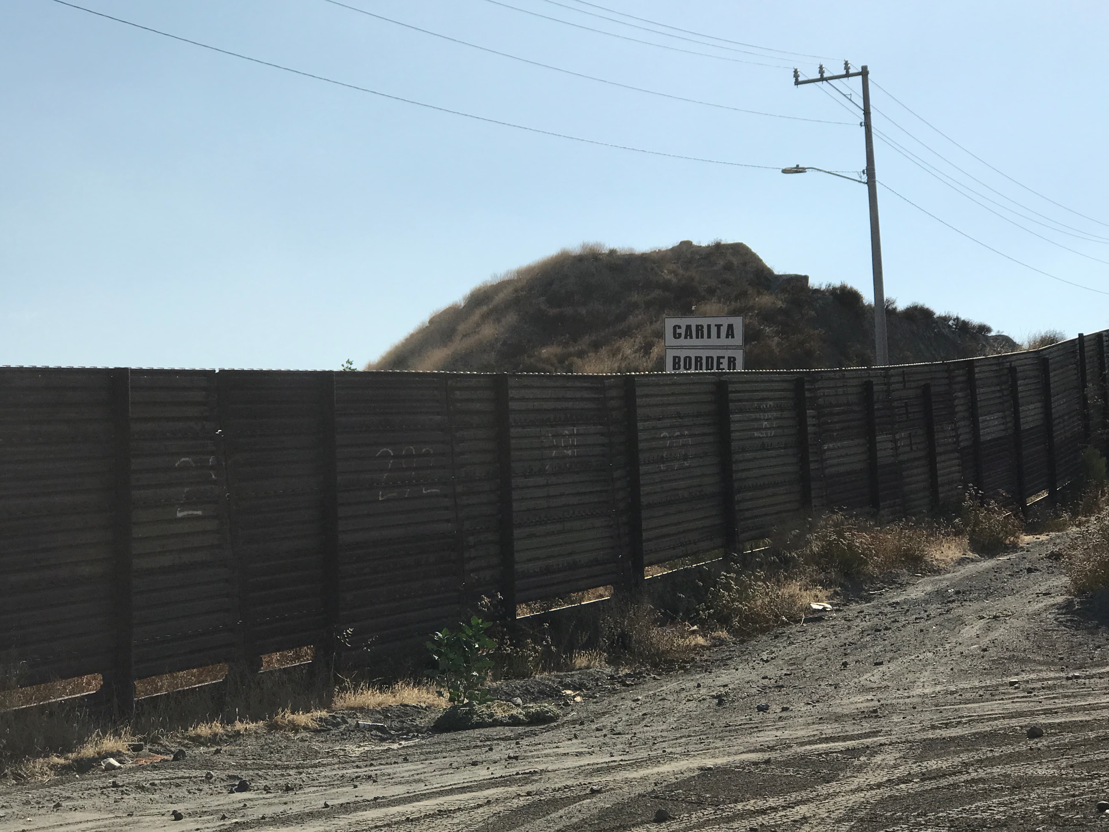 A wooden fence going through a desert landscape with electrical wires above