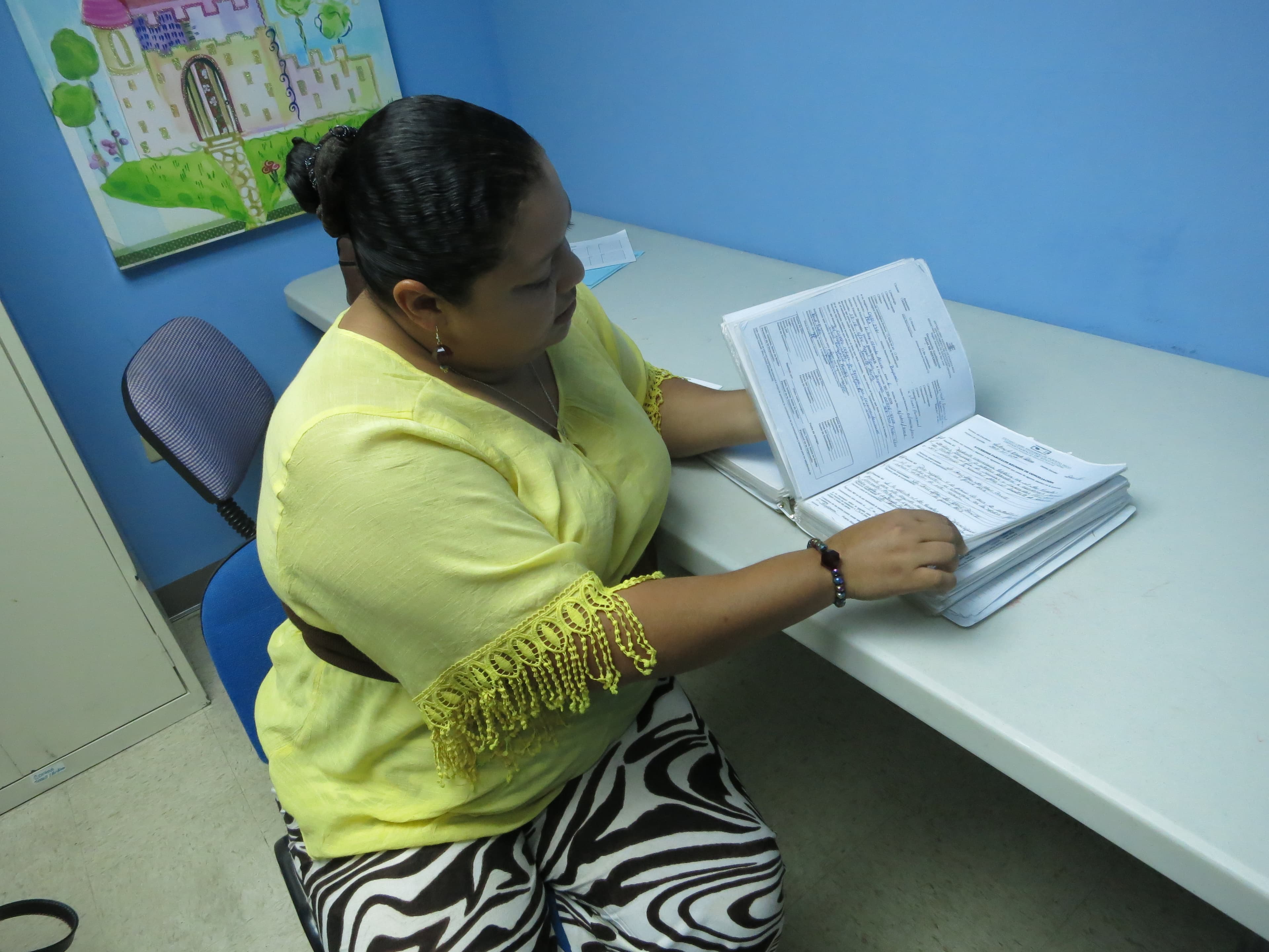 Jeanette Alicia Fernandez flips through a binder chronicling her battles with the Puerto Rican government to try and get services for her daughter with special needs.