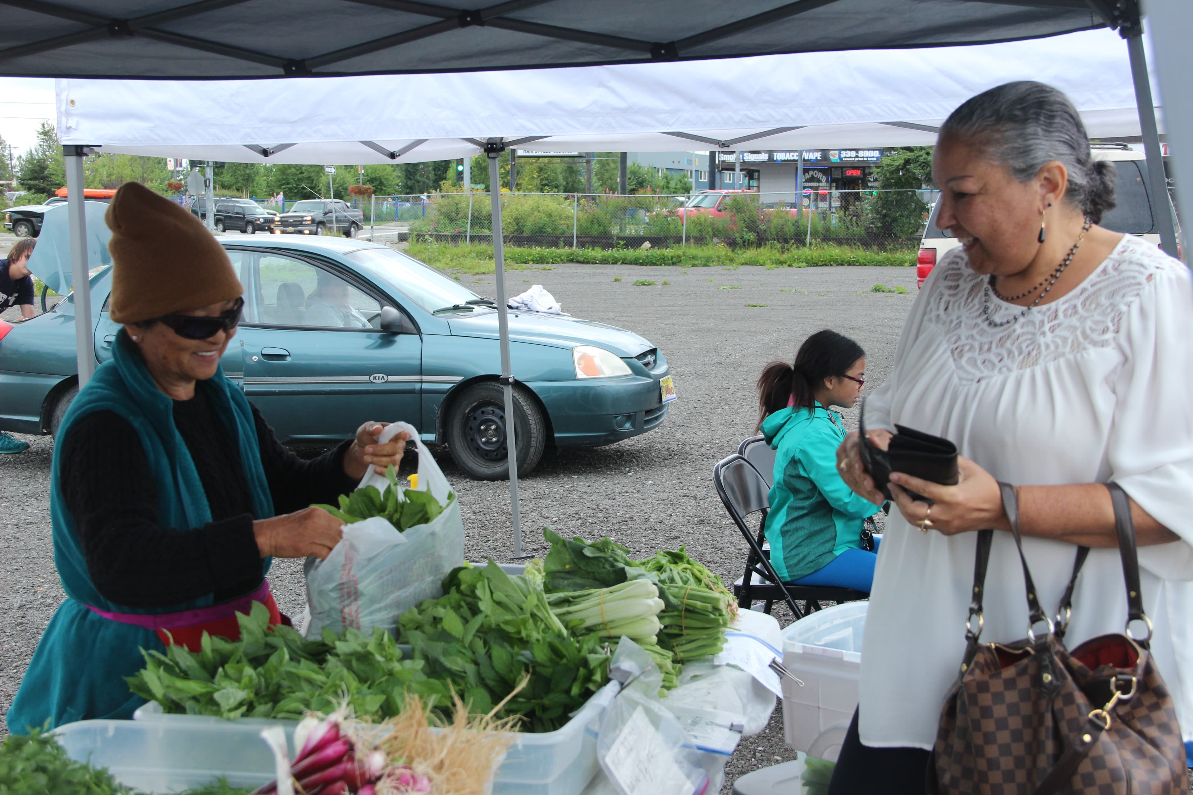 Angela Jimenez (right) buying vegetables at Mountain View’s weekly farmer’s market.