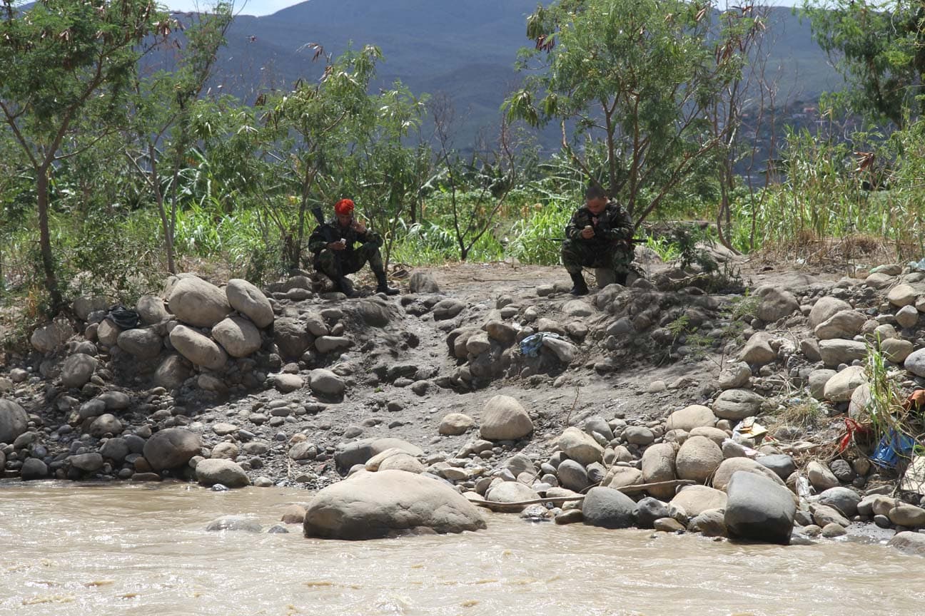 Venezuelan national guard soldiers stand guard by the river .