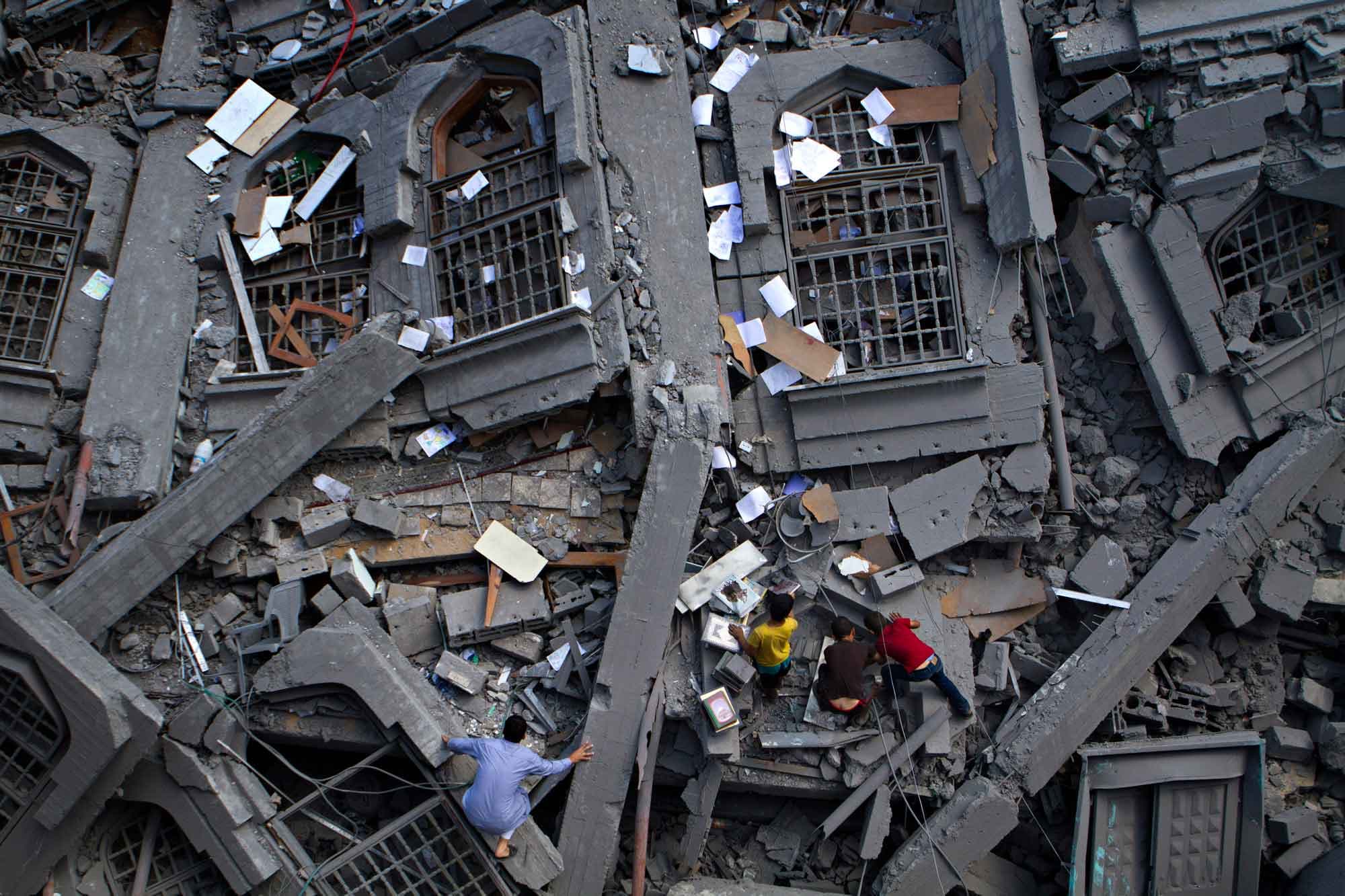 Palestinians collect religious books in the rubble of the Al-Qassam mosque in Nuseirat camp located in the middle of the Gaza Strip, July 9, 2014. Israeli warplanes carried out 30 air strikes over Gaza on Saturday.