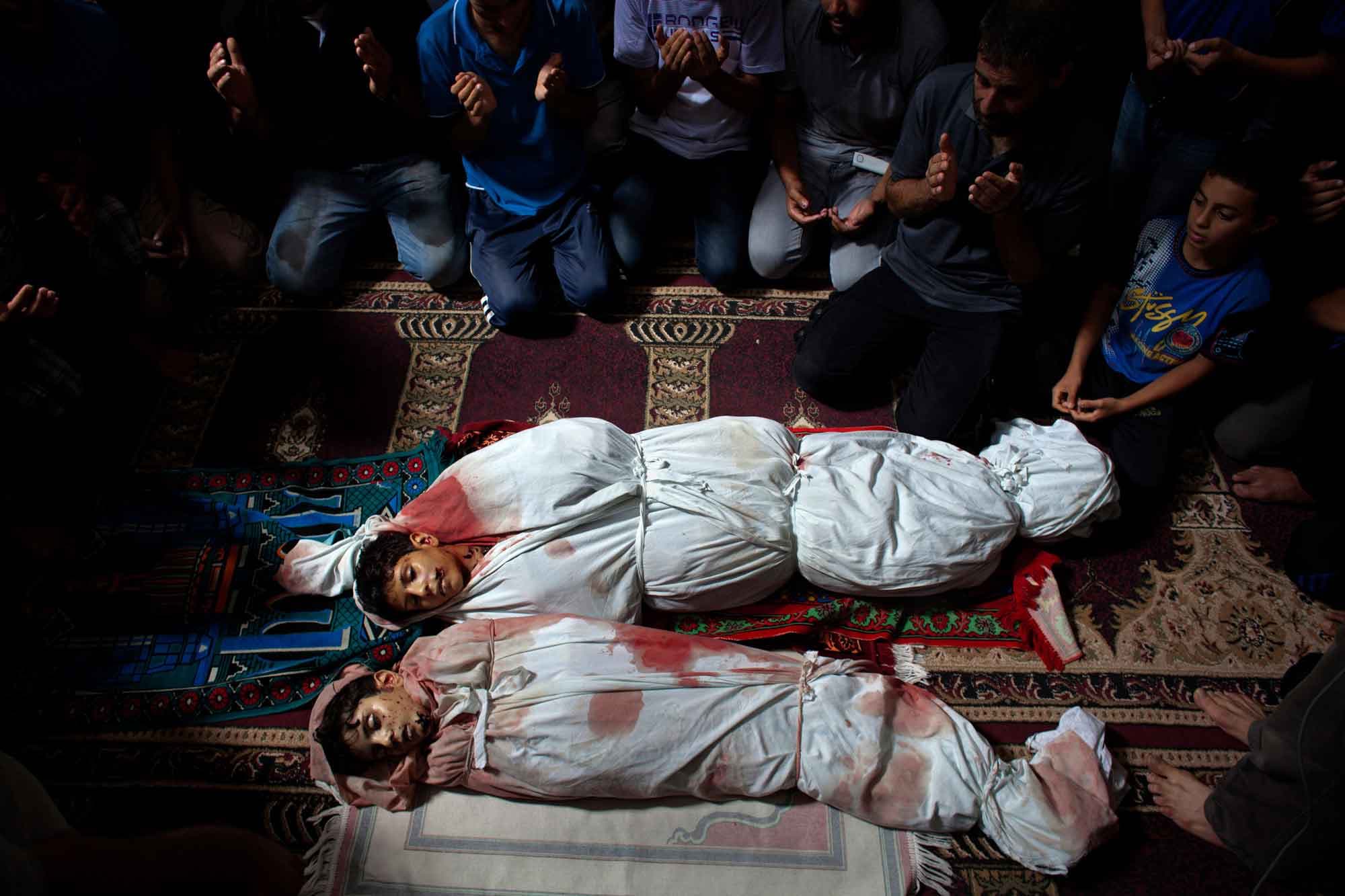 Family members surround and pray over the bodies of Palestinian brothers Amir Mustafa Arief, 15, and Mohamed Arief, 12, during their funeral at a mosque in the Shejaiya neighborhood of Gaza City, July 9, 2014. The two teens were killed together, near thei