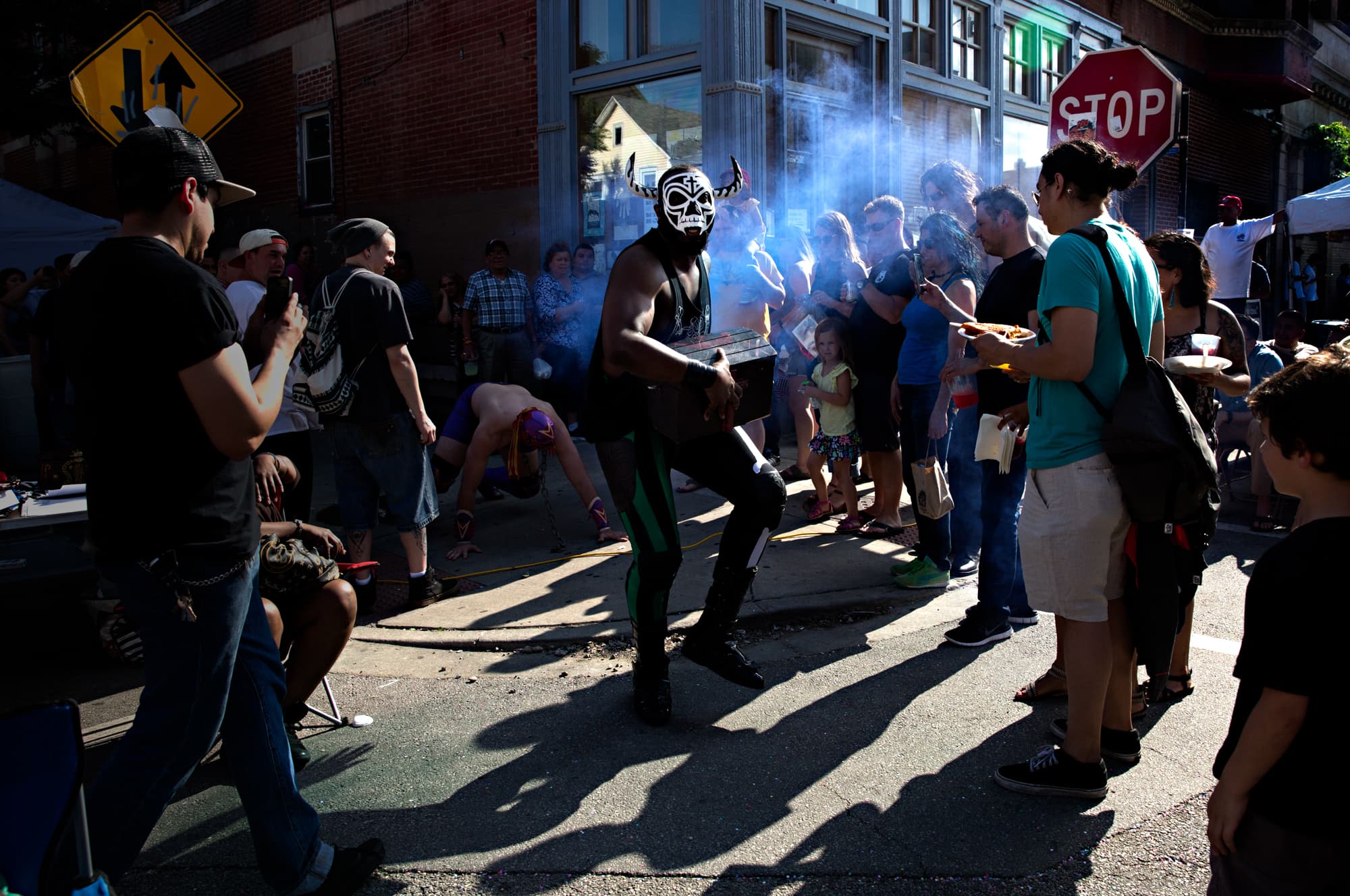 Man in mask looks toward camera, with crowd around him
