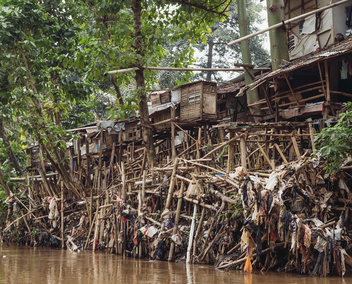 Slums line the Ciliwung river, one of 13 that run through Jakarta. Trash accumlated on the banks shows the high water mark during monsoon season.