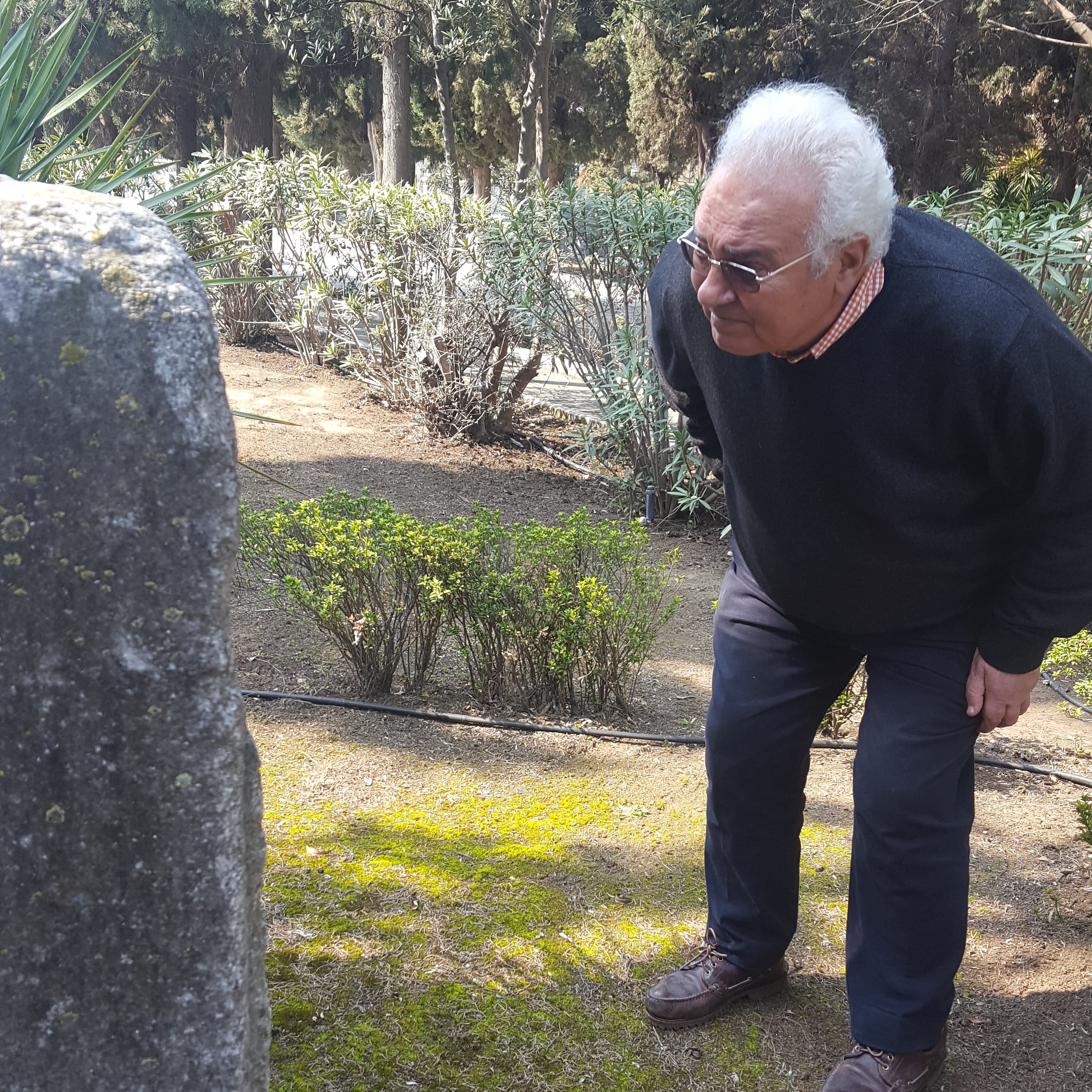 Jacky Benmayor stoops down to get a better look at an old tombstone at the newer Jewish cemetery.