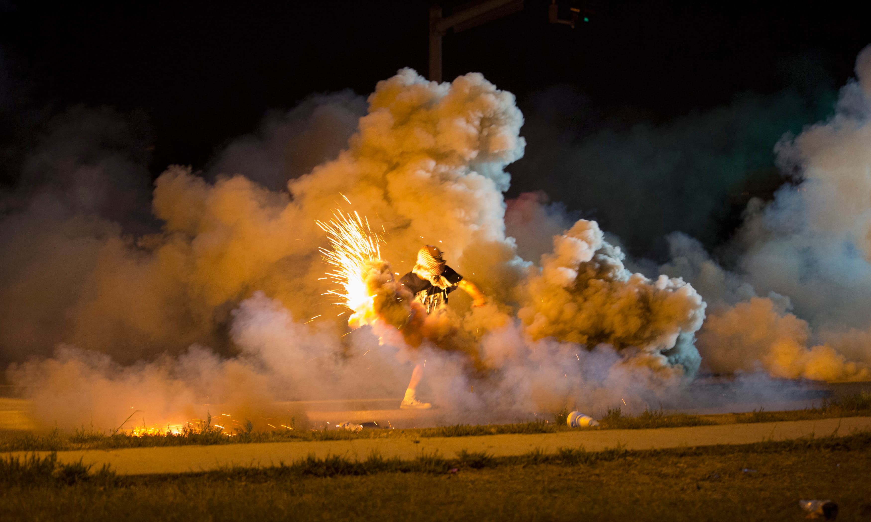 A protester throws back a smoke bomb while clashing with police in Ferguson, Missouri, on August 13, 2014.
