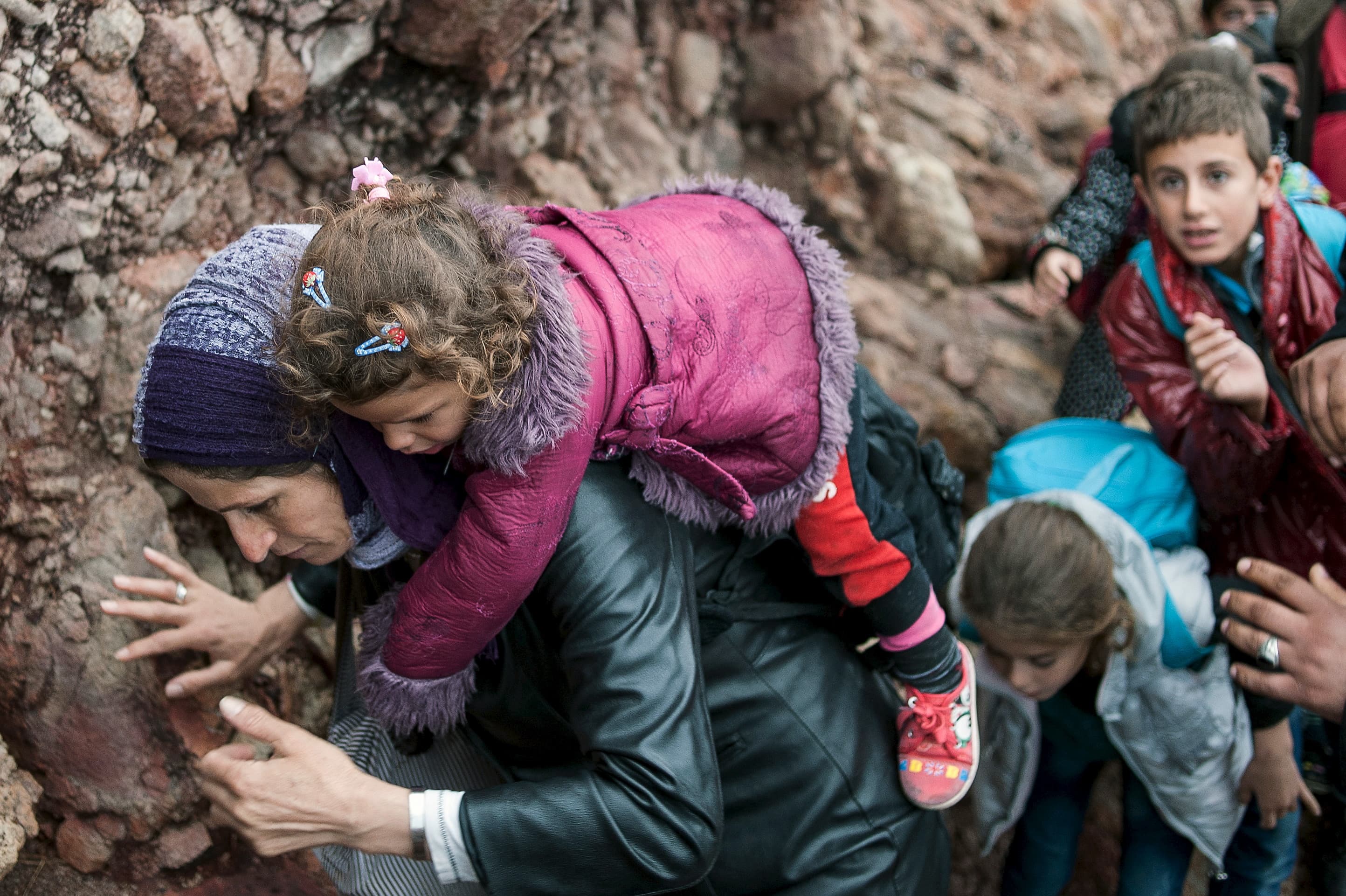 A migrant woman carries her child after arriving at a rocky beach on the Greek island of Lesbos after crossing a part of the Aegean Sea from the Turkish coast to Lesbos.