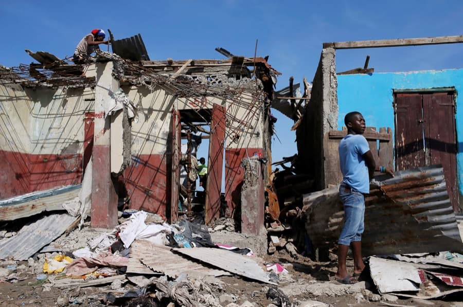 Men salvage metal sheets from a destroyed house after Hurricane Matthew ravaged Jeremie, Haiti.