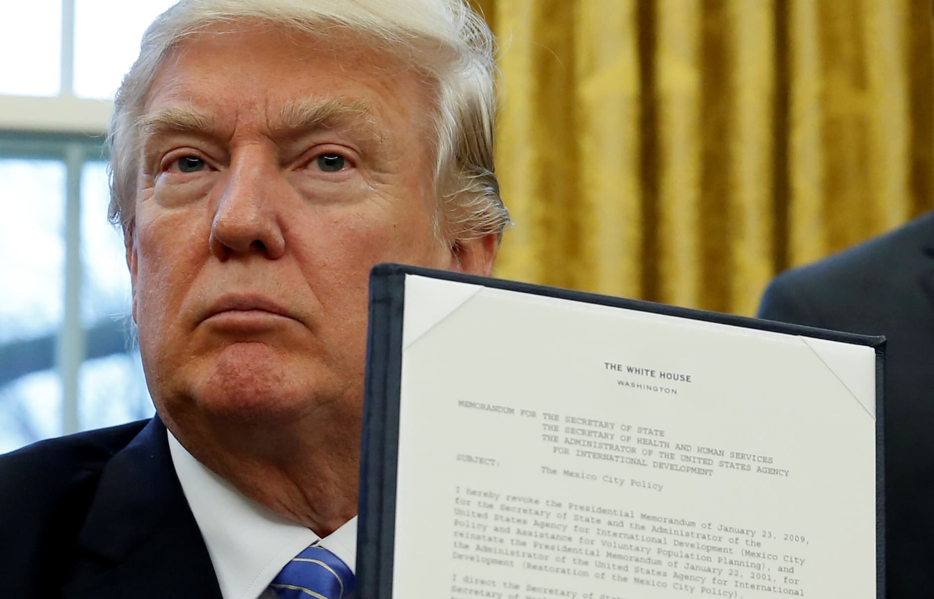 U.S. President Donald Trump holds up his executive order on the reinstatement of the Mexico City Policy.