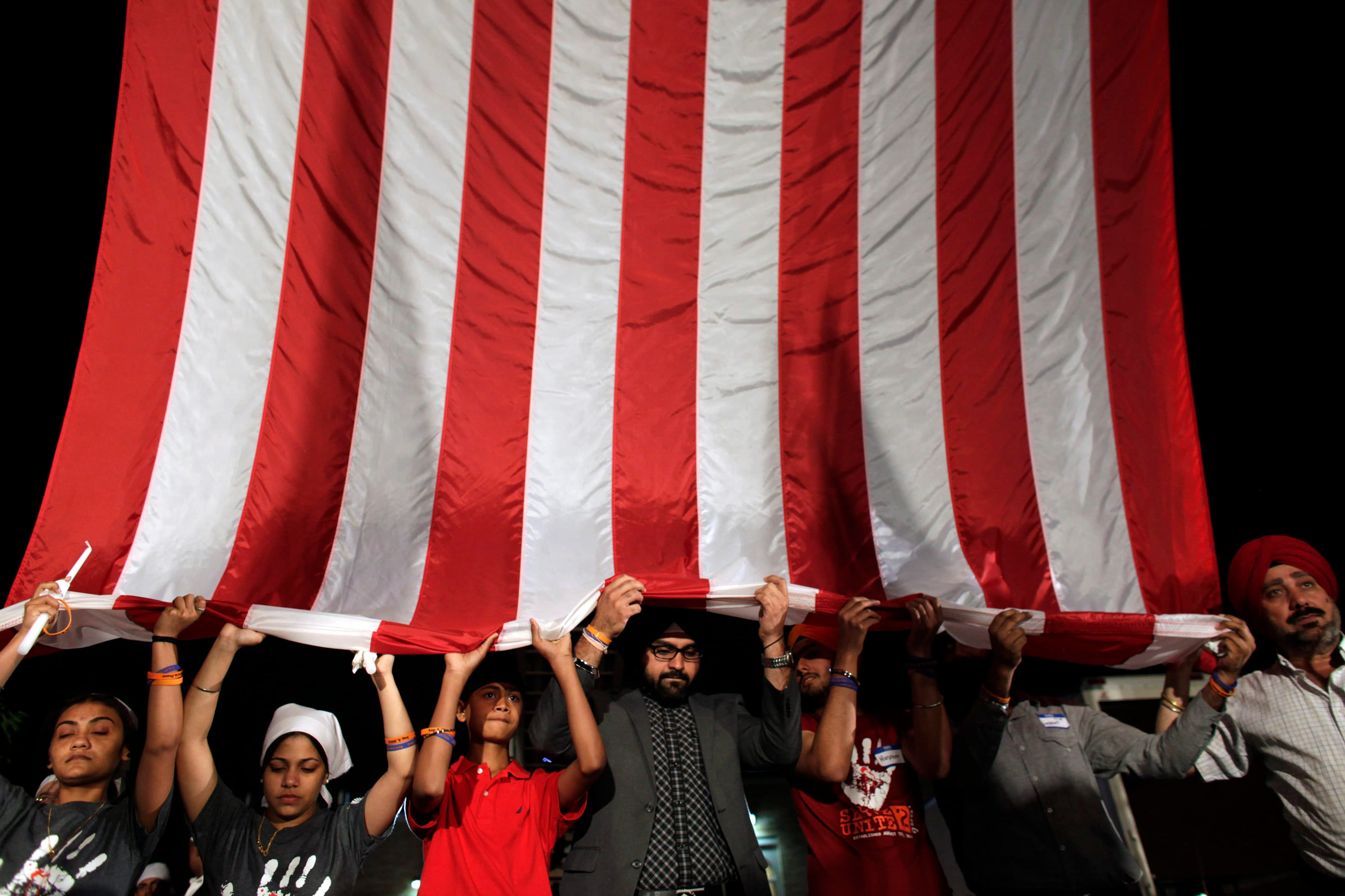 Large American flag held from the bottom by line of people