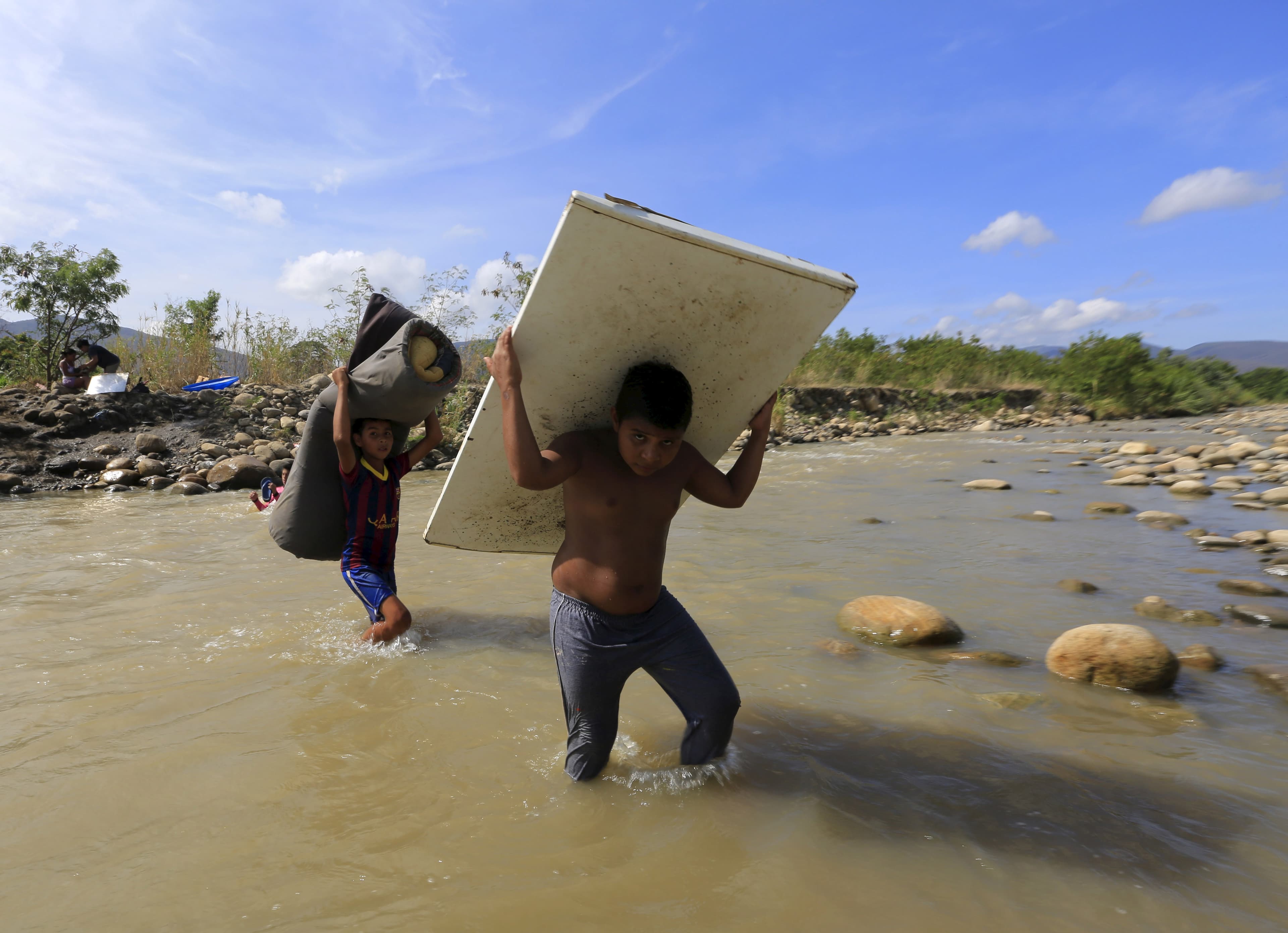 Boys carry their belongings as they cross the Tachira river border into Colombia from Venezuela, near Colombia's Villa del Rosario village, August 27, 2015.