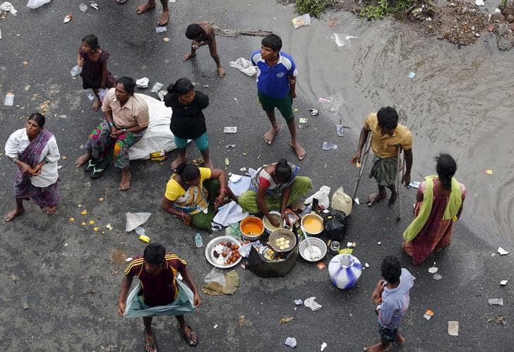 ​Displaced residents cook their meal on a flooded roadside in Chennai, India, December 3, 2015.