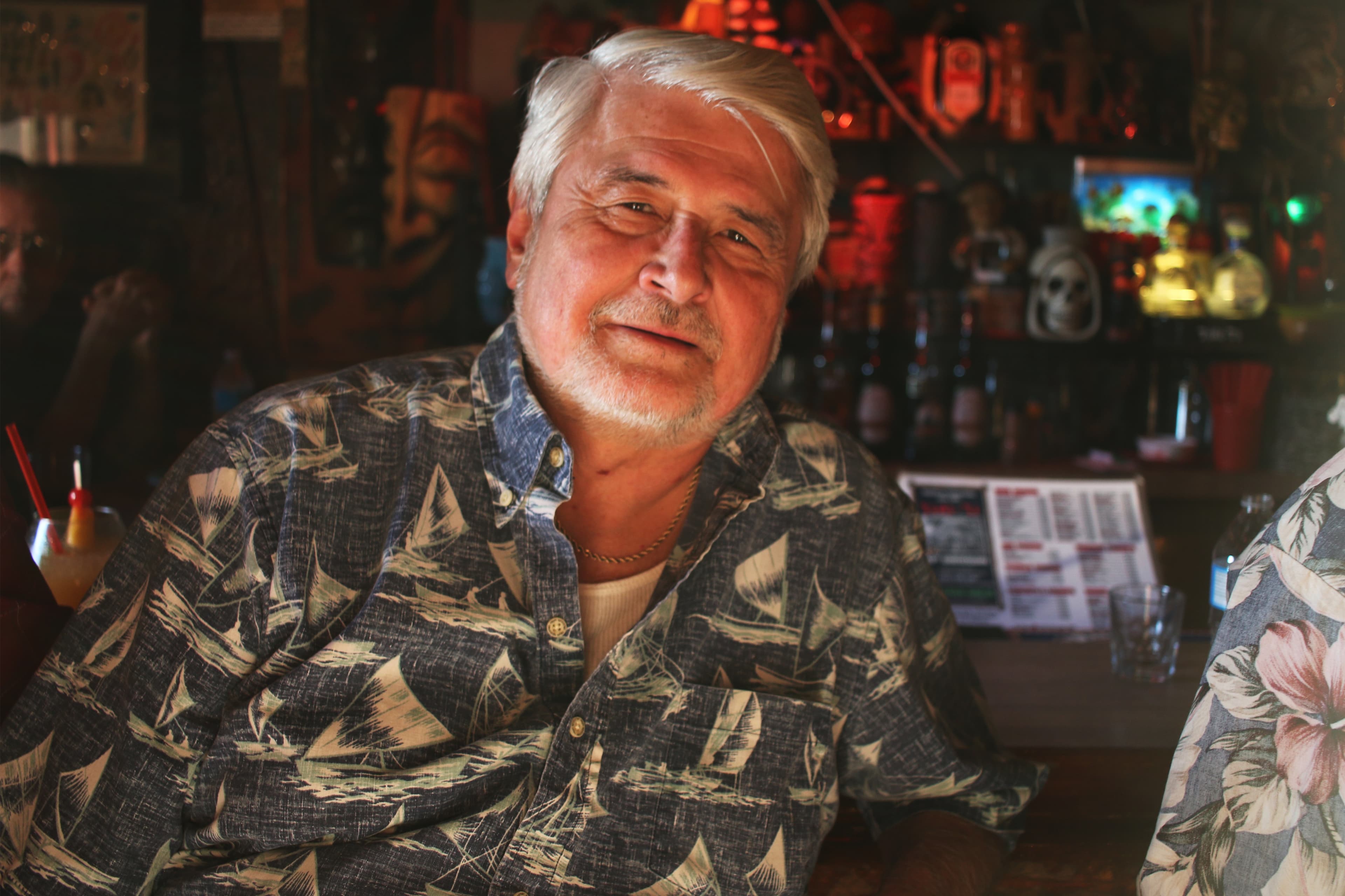 Smiling man in Hawaiian button-down shirt, looking at camera