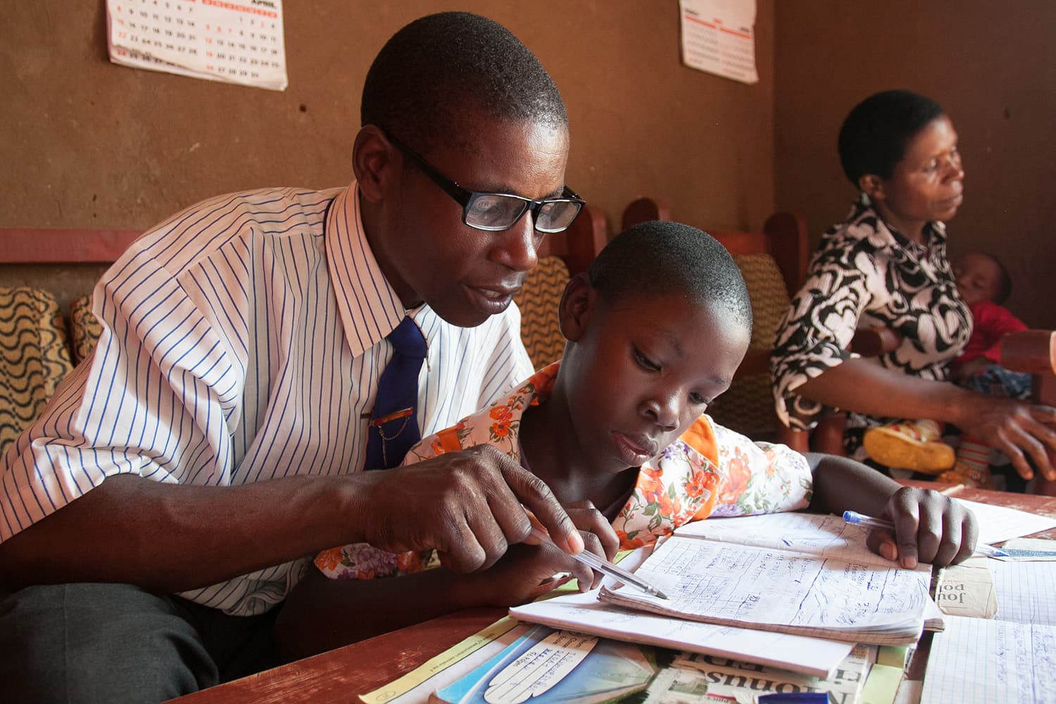 Teacher with glasses, helps student.