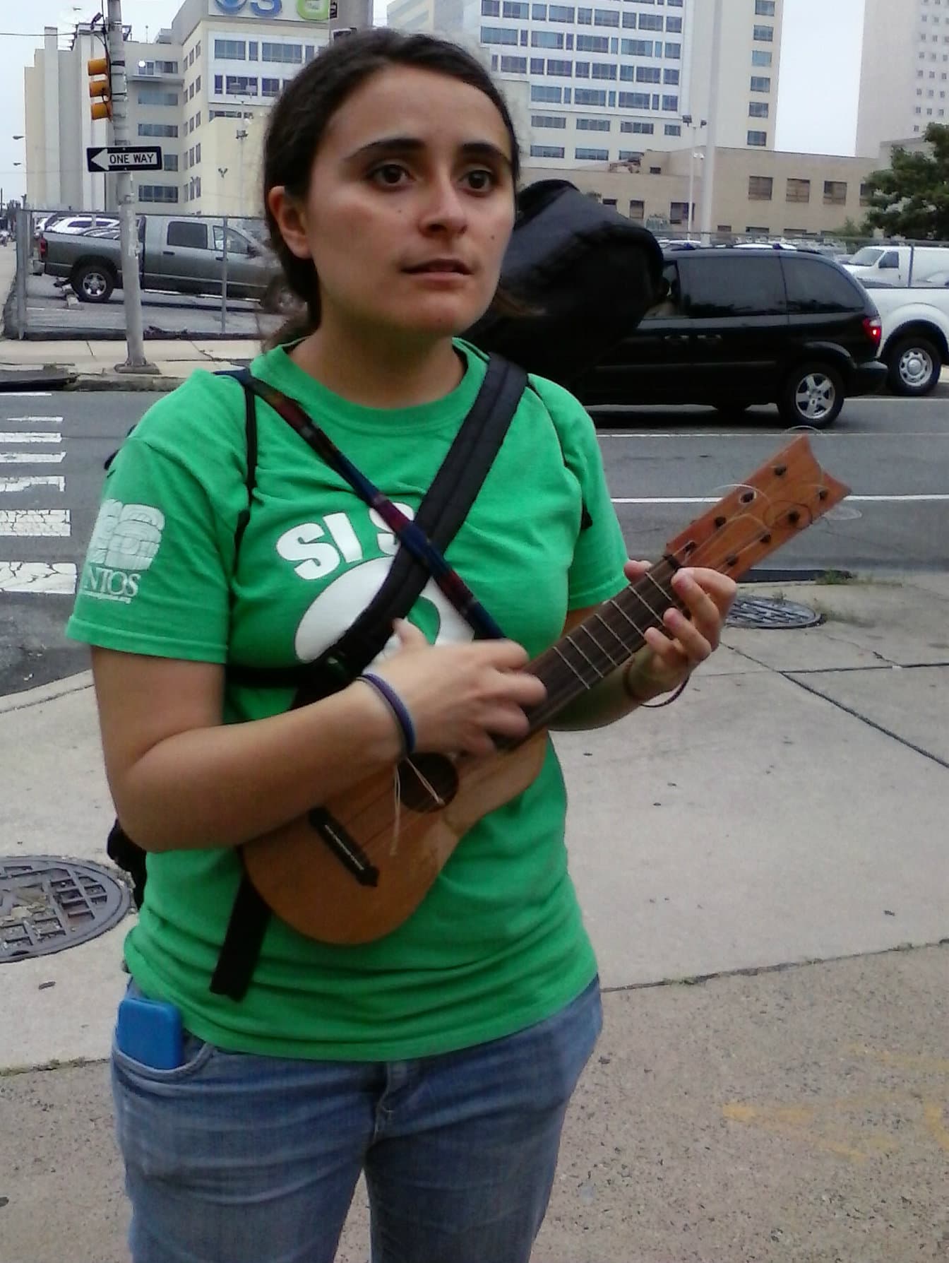 Yared Portillo plays a jarana while standing on a street corner.