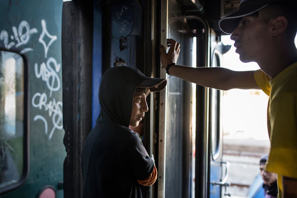 A boy and young man inside a train car parked at Idomeni station.