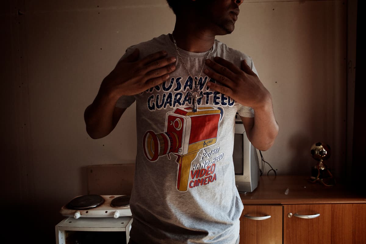 Abraham, 25 and unemployed, displays a silver crucifix.