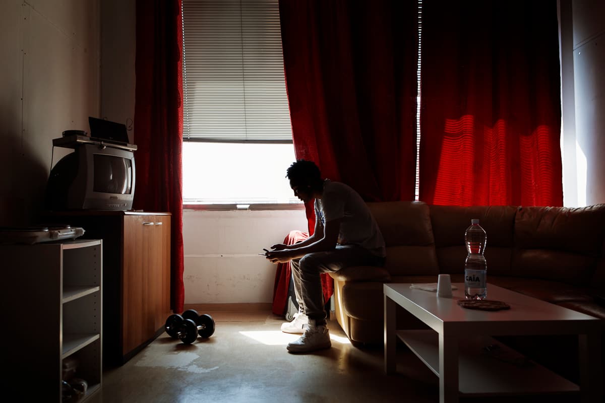 Abraham, 25 and unemployed, peers at his cell phone.