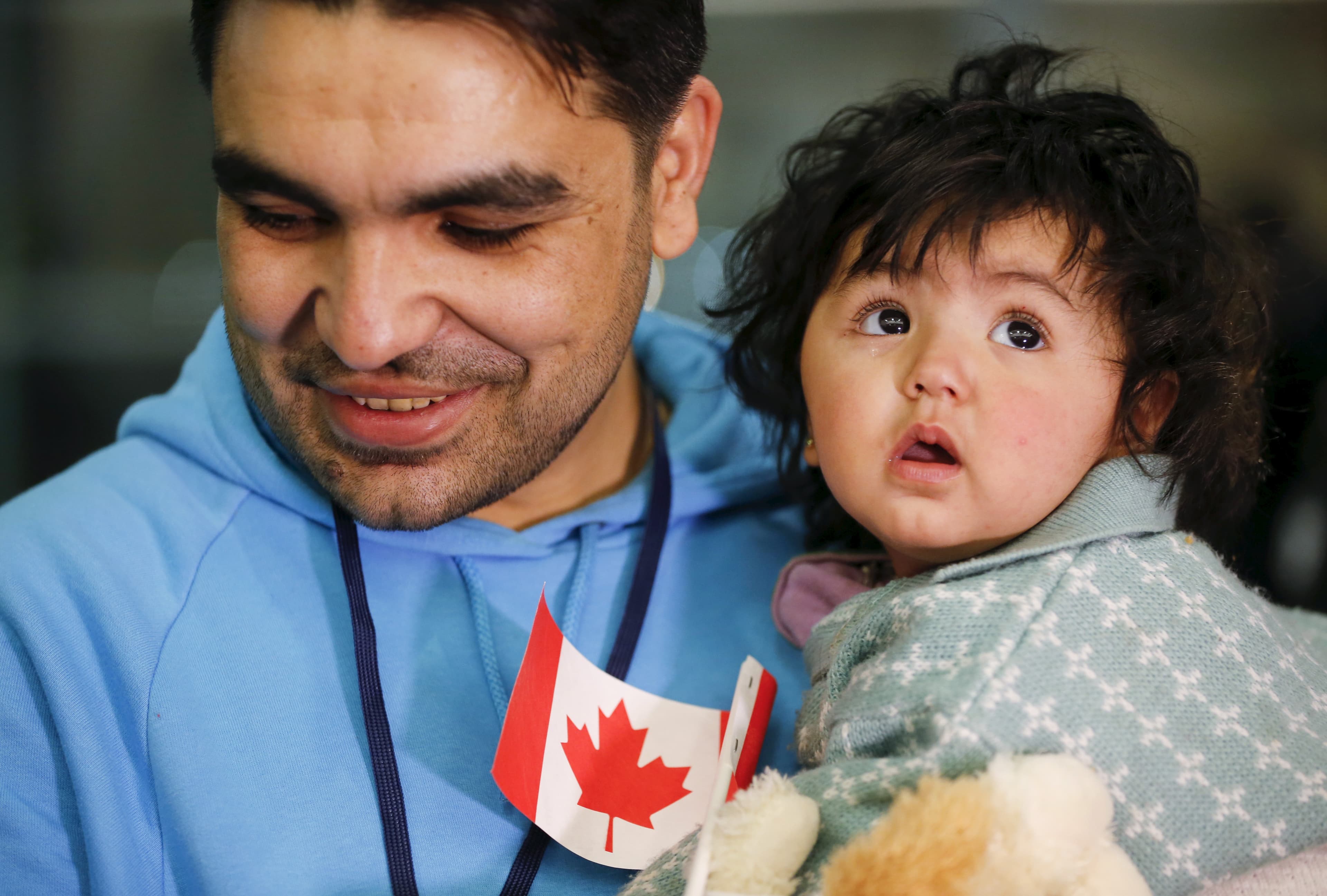 A Syrian refugee holds his daughter as they arrive at the Pearson Toronto International Airport in Mississauga, Ontario, December 18, 2015.