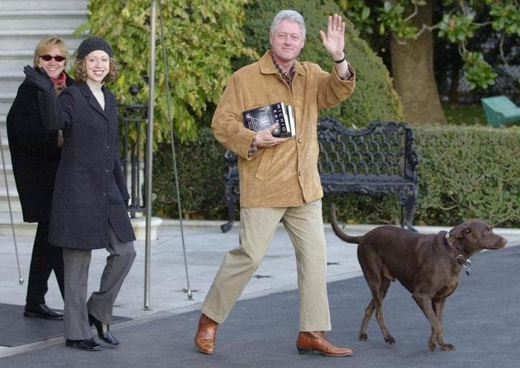 President Bill Clinton and First Lady Hillary Clinton, along with their daughter, Chelsea, wave at the camera as they depart the White House with the dog Buddy leading the way.